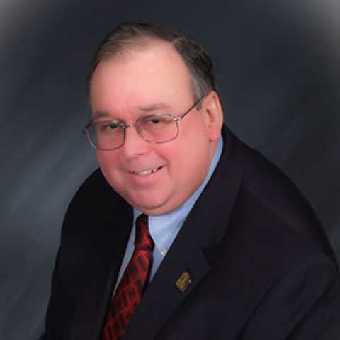 A man in a suit and tie is smiling for the camera.