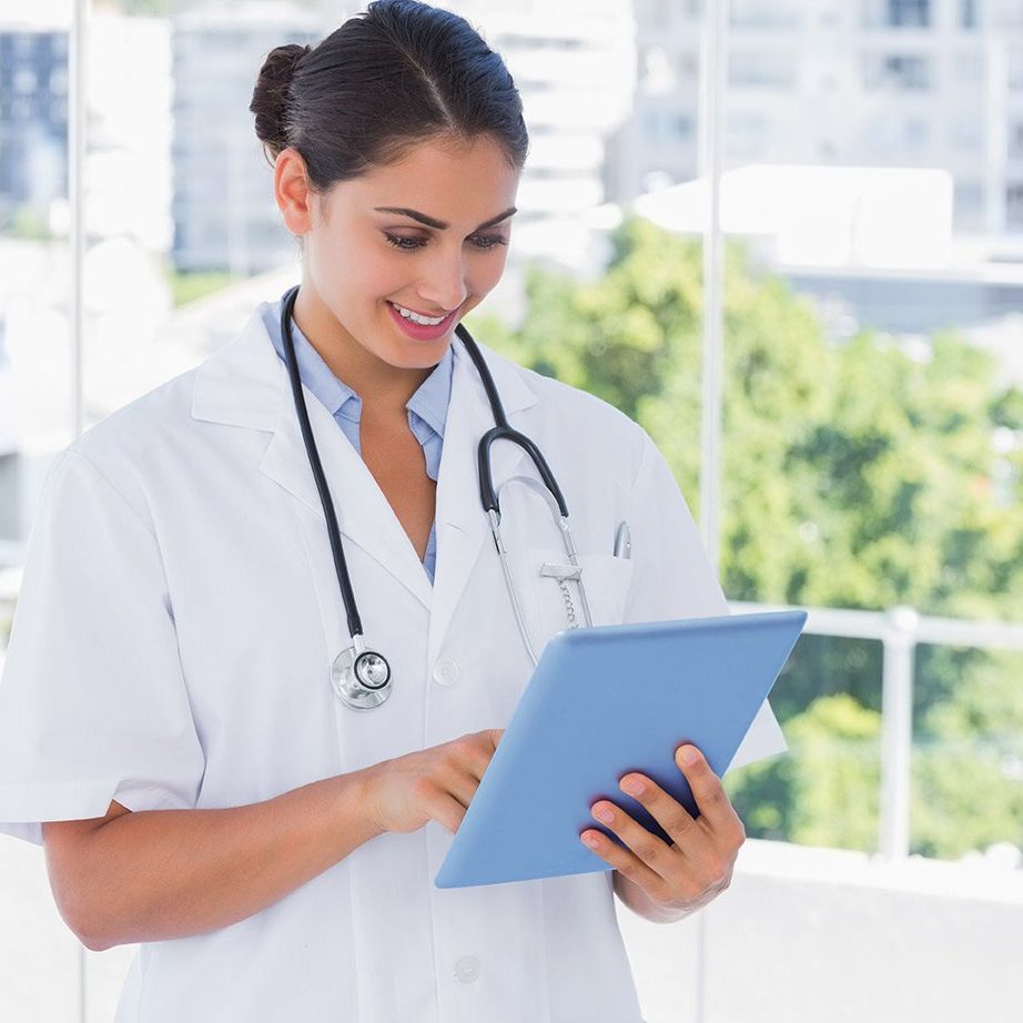 A female doctor with a stethoscope around her neck is using a tablet computer