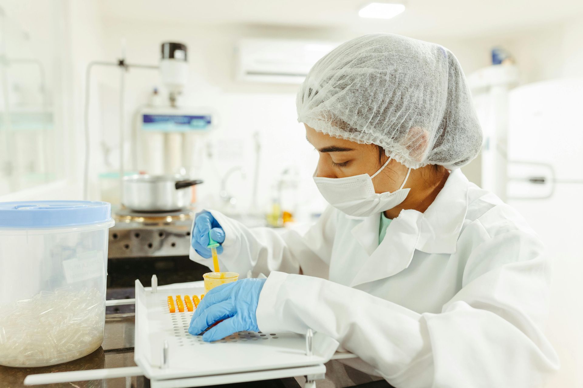 A female scientist wearing a mask and gloves is working in a laboratory.