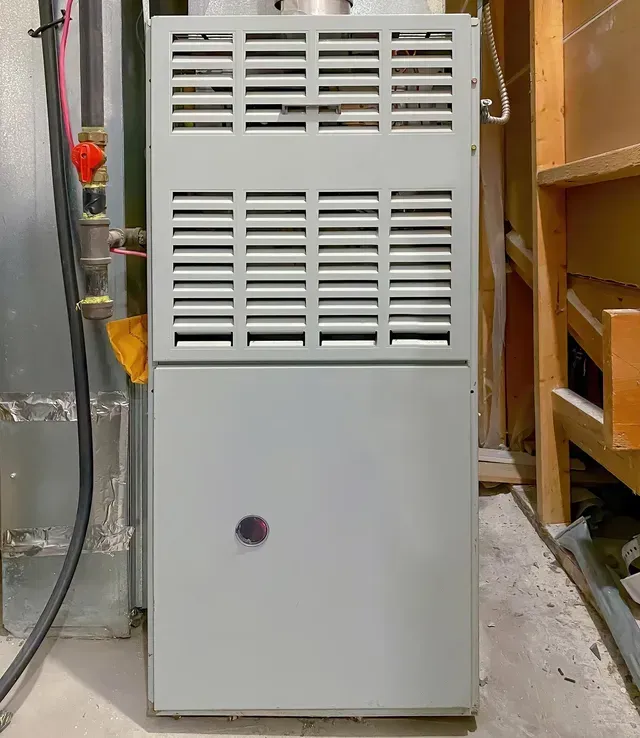 A furnace is sitting in a corner of a room.