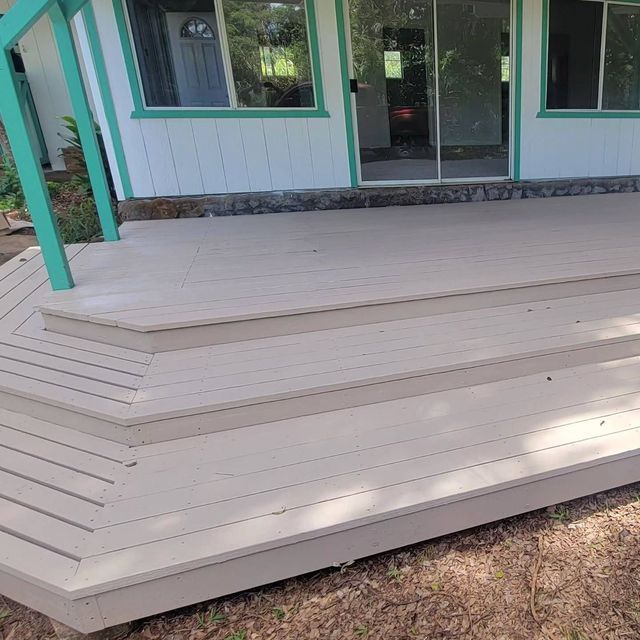 Wooden porch deck with steps and teal trim in front of a house