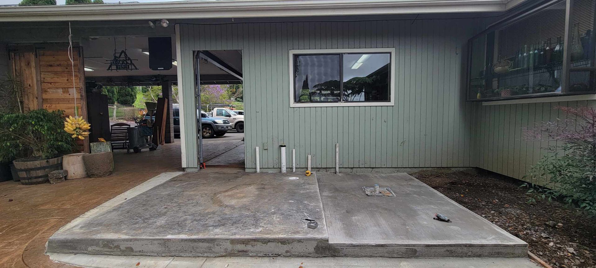 A building exterior with a concrete slab, open doorway, and a window.