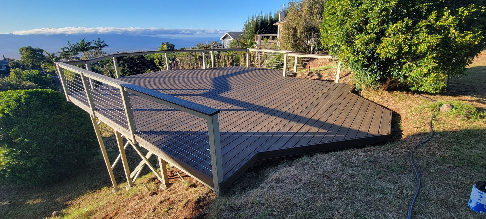 Wooden deck with railings overlooking a scenic view of a cloud-covered mountain range and greenery.