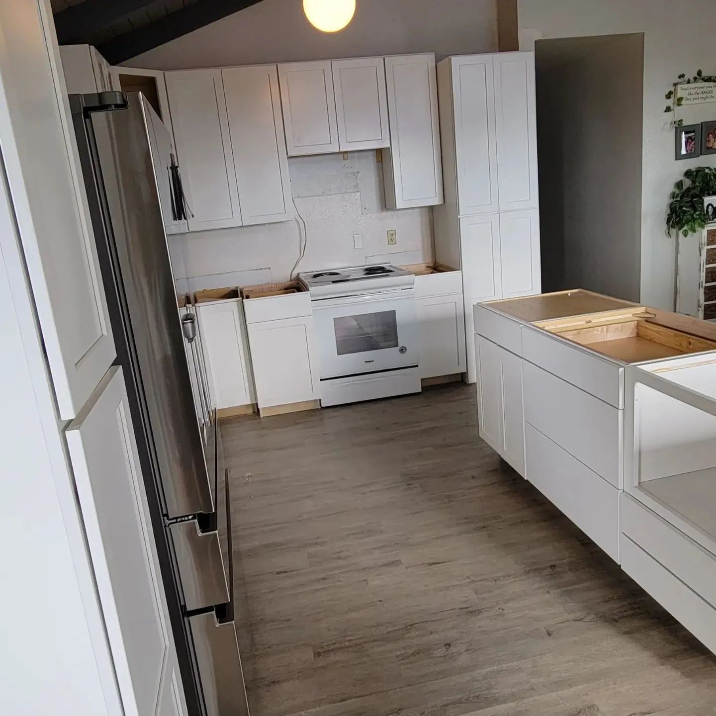 Bright modern kitchen with white cabinets, stainless fridge, and unfinished island countertop