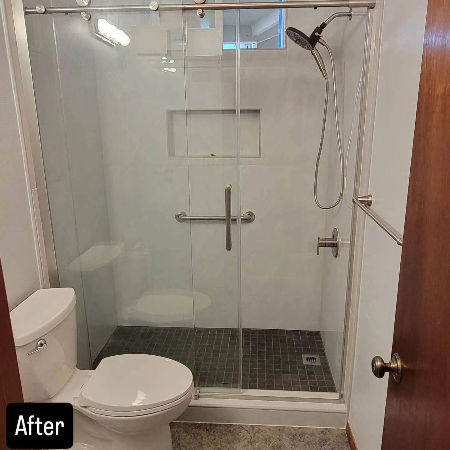 Compact bathroom with glass walk-in shower, wall-mounted toilet, and tiled floor.
