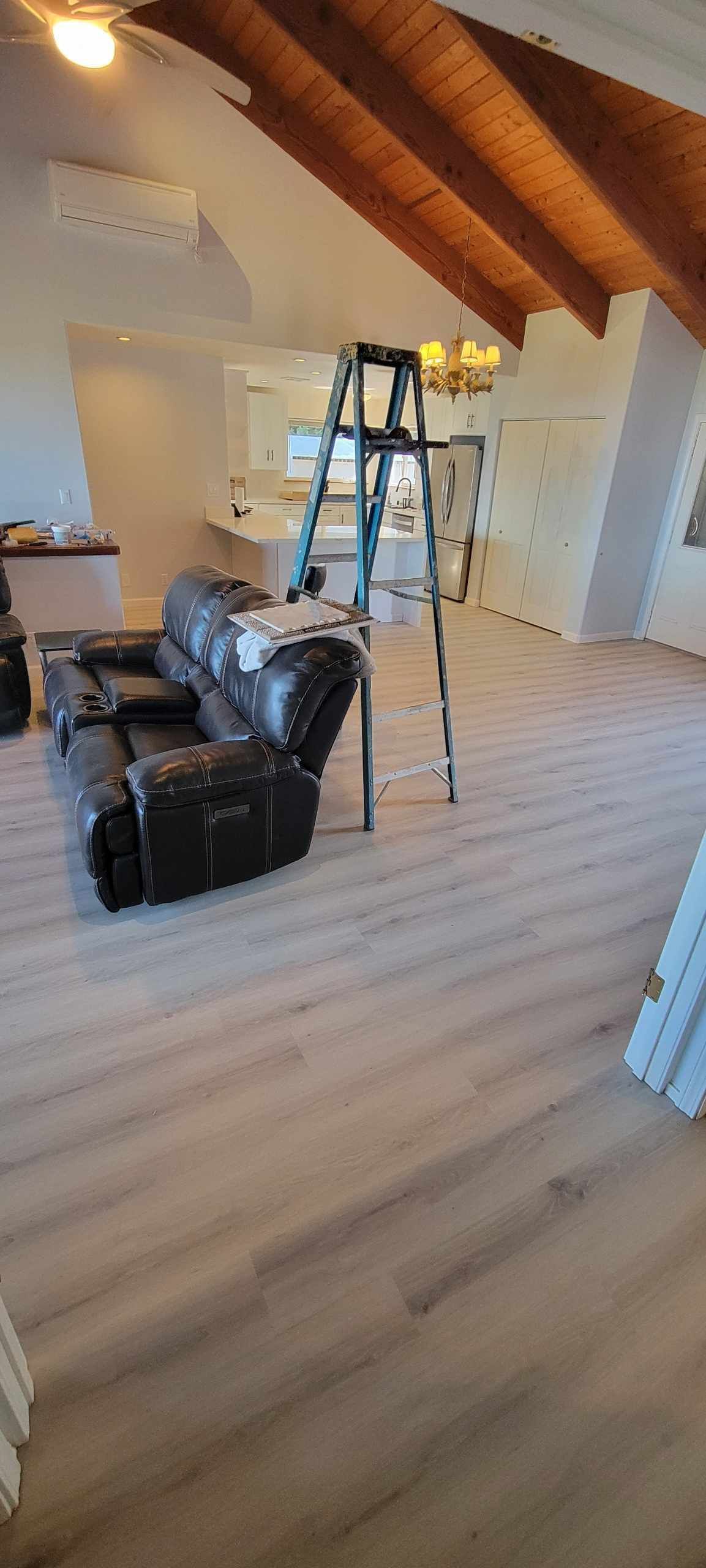 Interior view of a room with hardwood floors, a recliner, and a ladder.