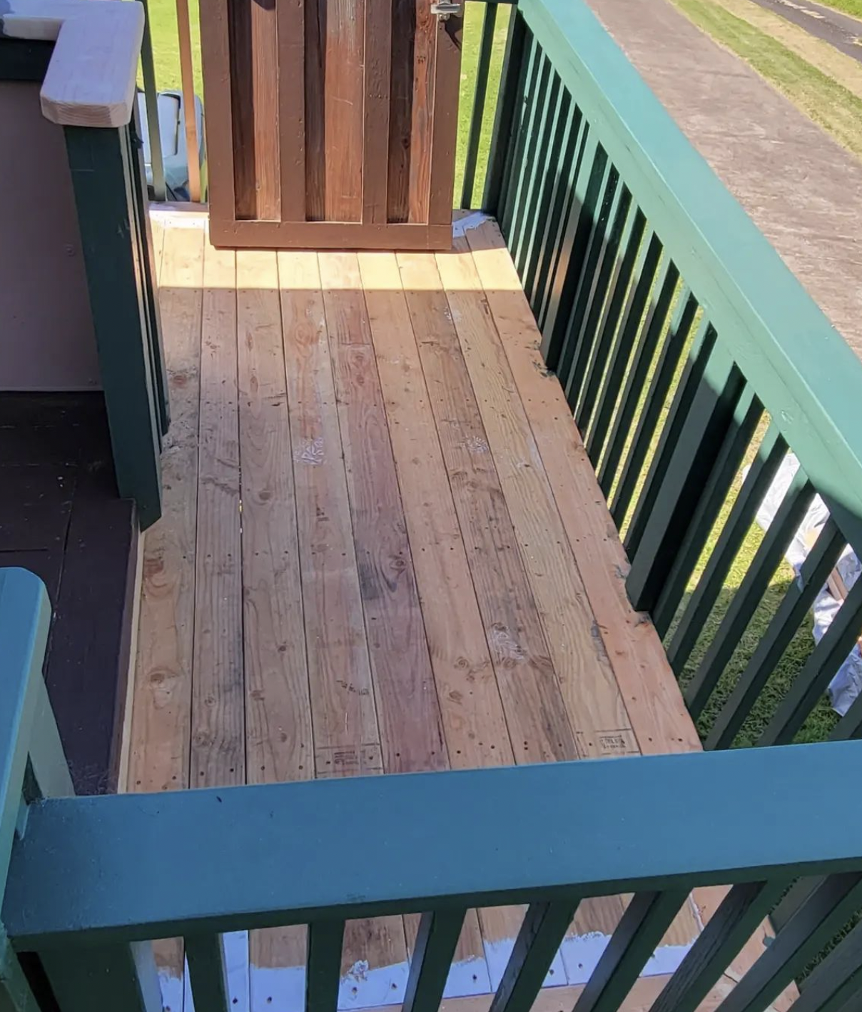 Wooden deck with green railing and gate.