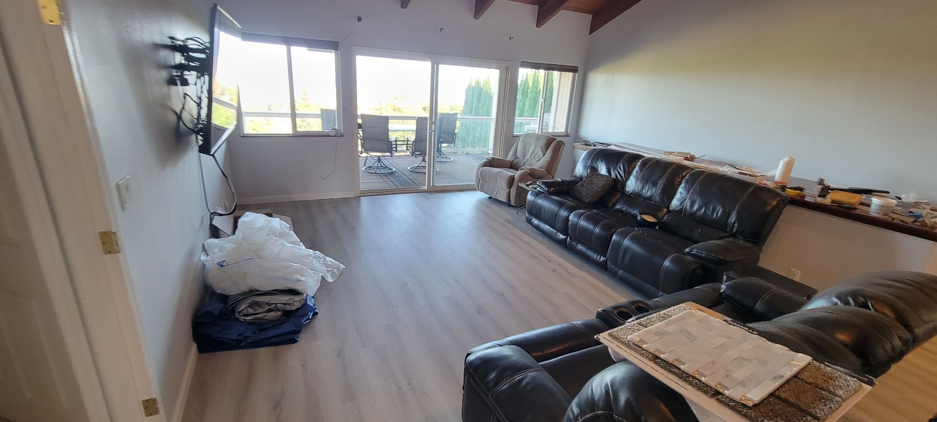 Living room with leather sofa, TV, and sliding glass doors leading to a balcony.