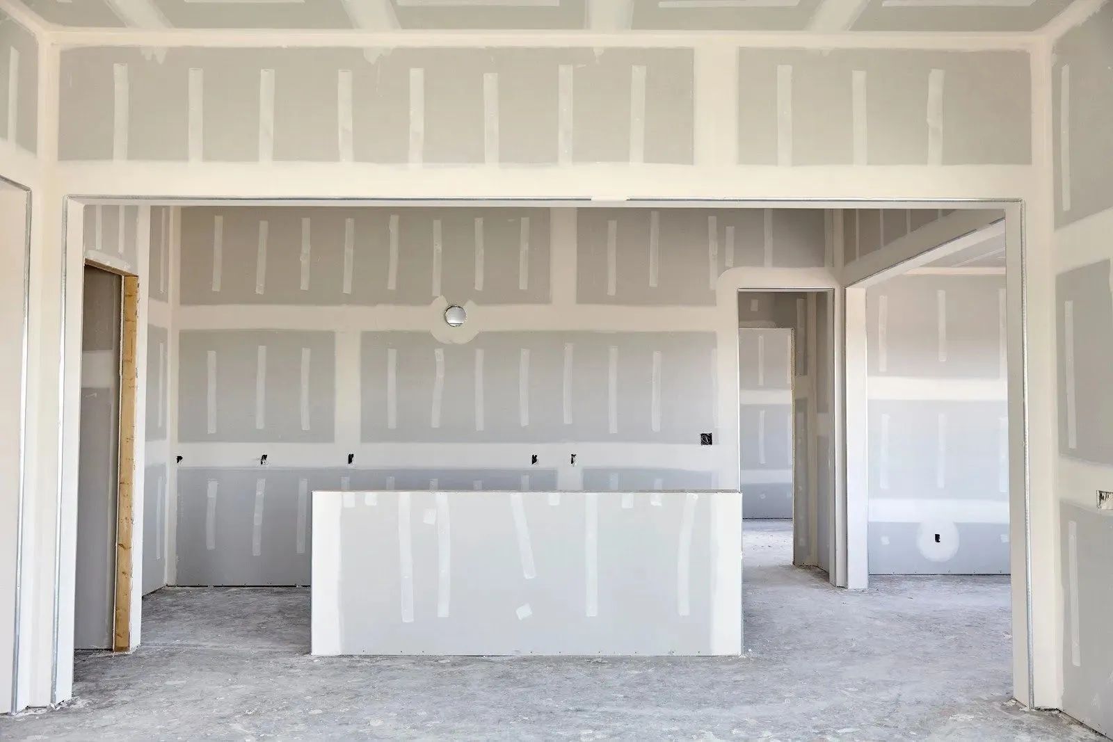 Unfinished kitchen with drywall, exposed framing, and a white island in the center.