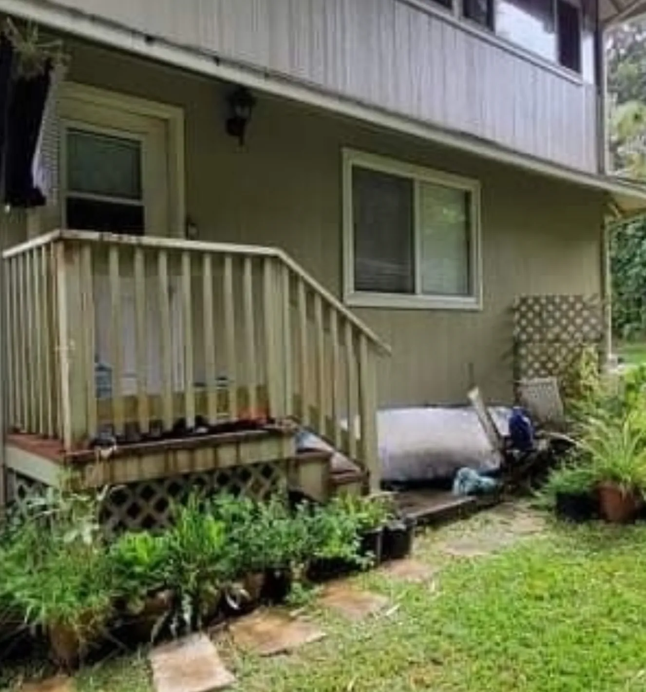 Small house porch with stairs, potted plants, and lawn in front