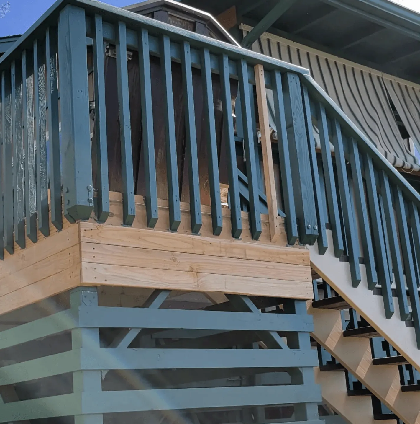 Blue wooden deck railing and stairs on the exterior of a house