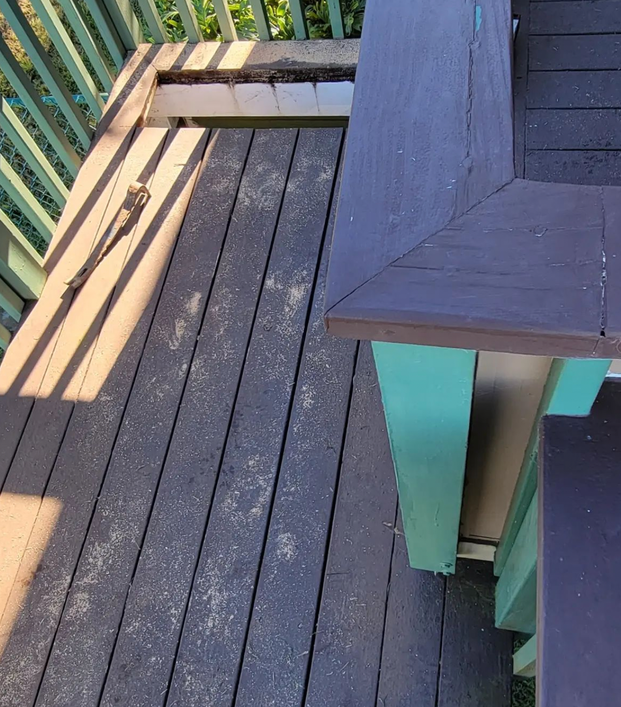 Sunlit wooden deck with benches and a dark-topped turquoise table