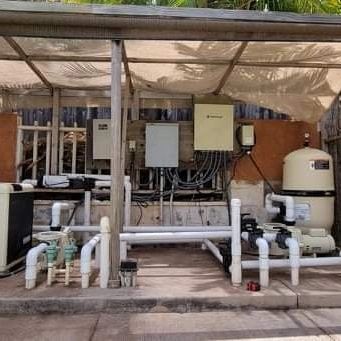 Outdoor industrial water treatment equipment with pipes, pumps, and control boxes under a canopy