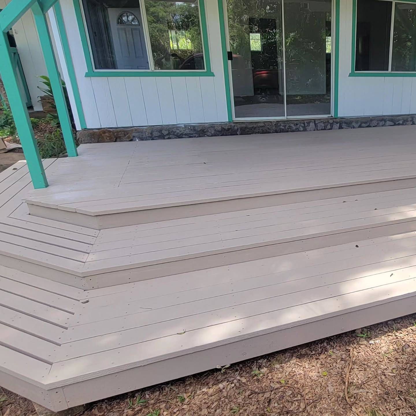 Wooden deck with three steps, painted beige, in front of a house with green trim.