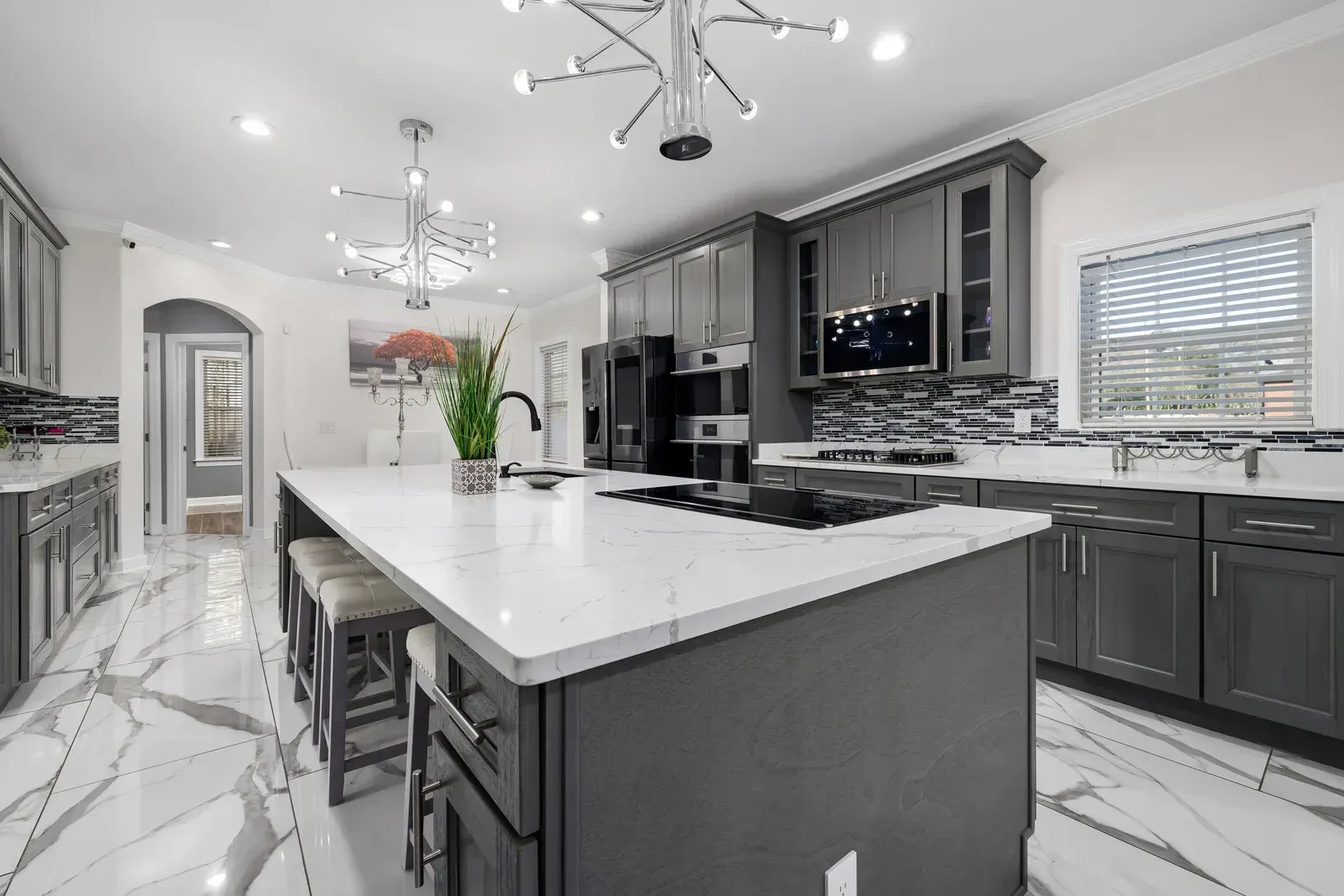 Modern gray kitchen with marble-look floors, a large island, and stainless steel appliances.