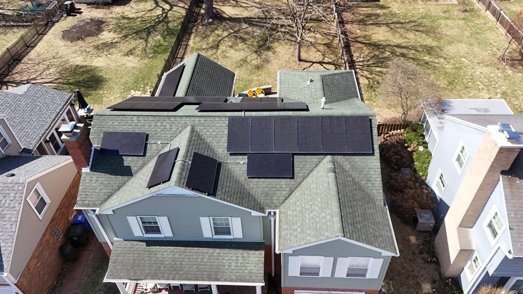 Solar panels installed on a two-story house roof, seen from above on a sunny day.