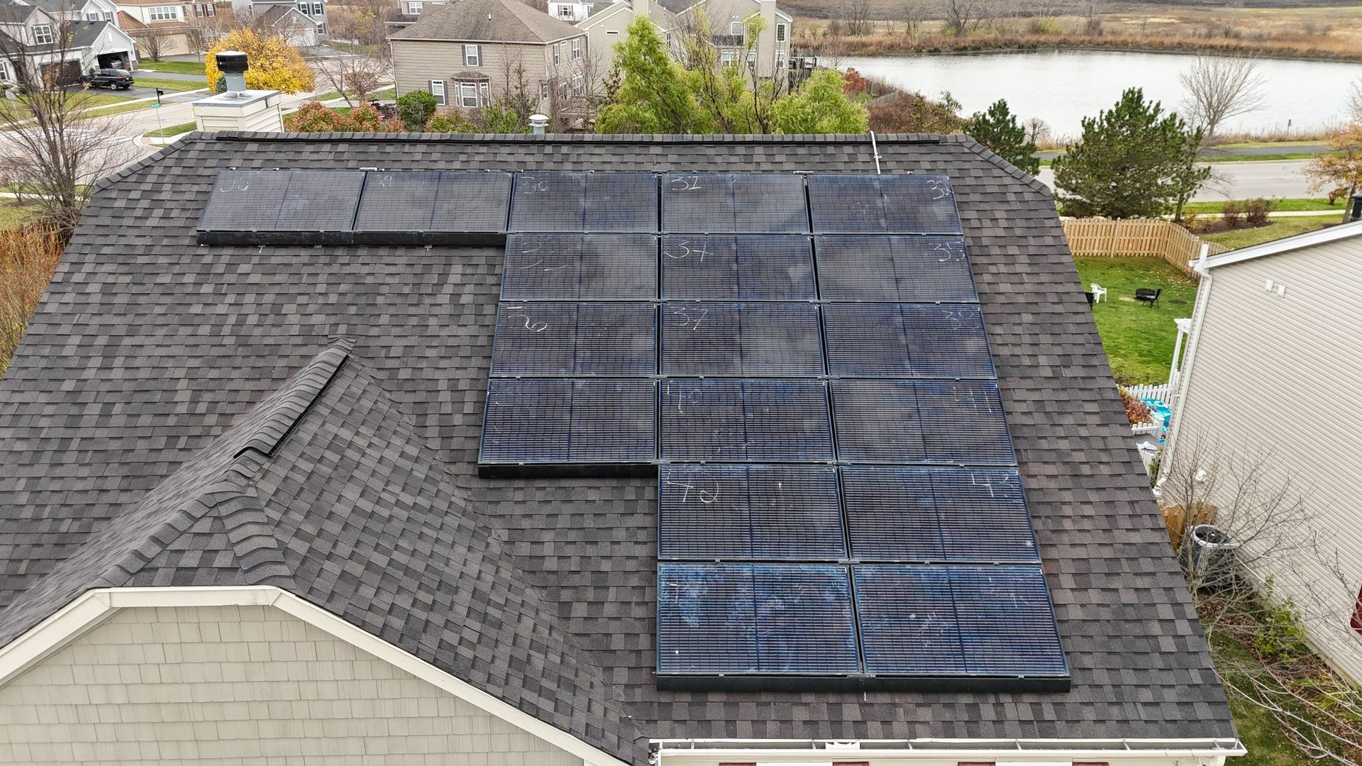 Solar panels on a dark shingled roof of a house in a residential area.