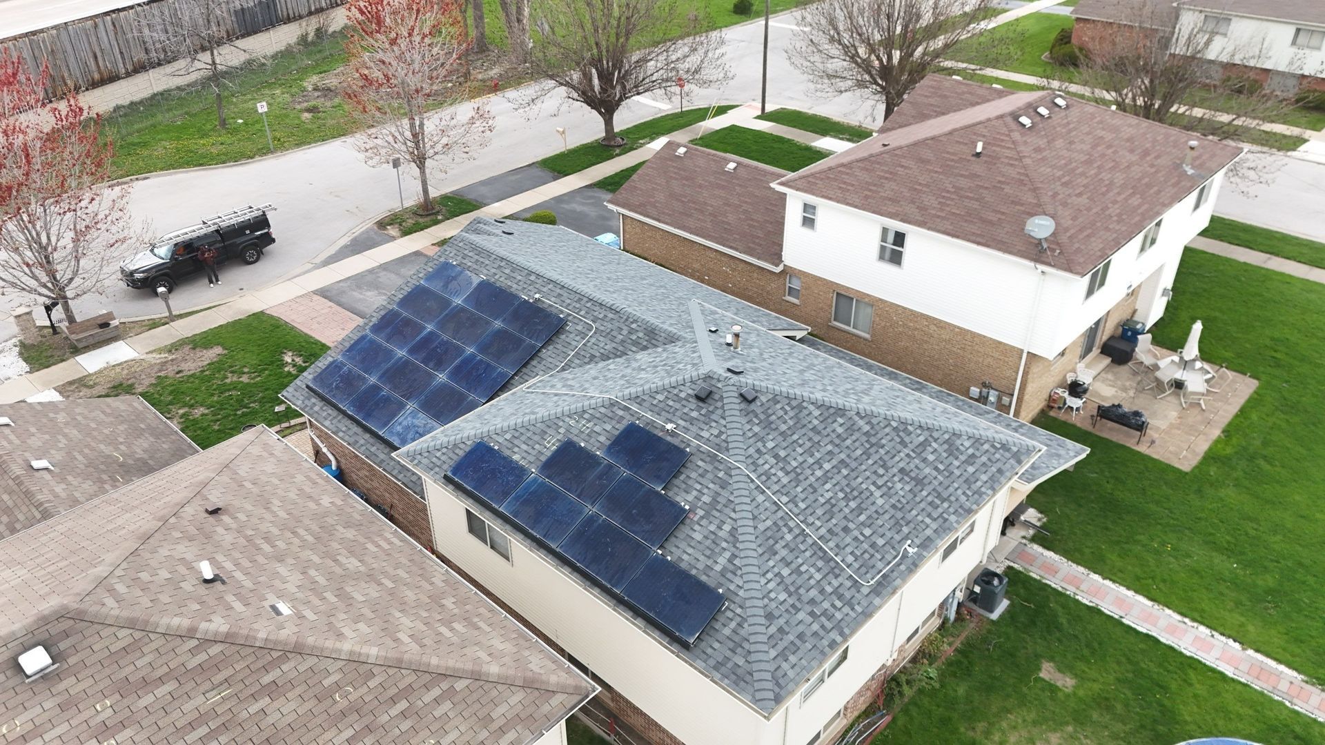 Aerial view of a house with solar panels on the roof in a residential neighborhood.