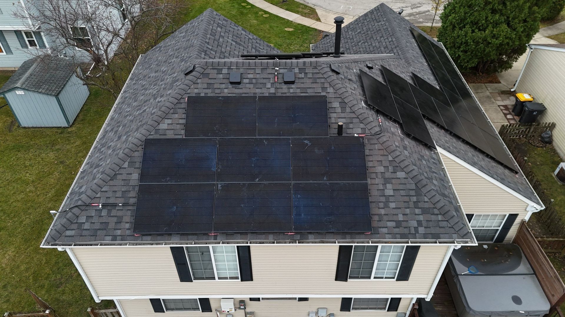 House roof with solar panels installed on a dark grey shingle roof.