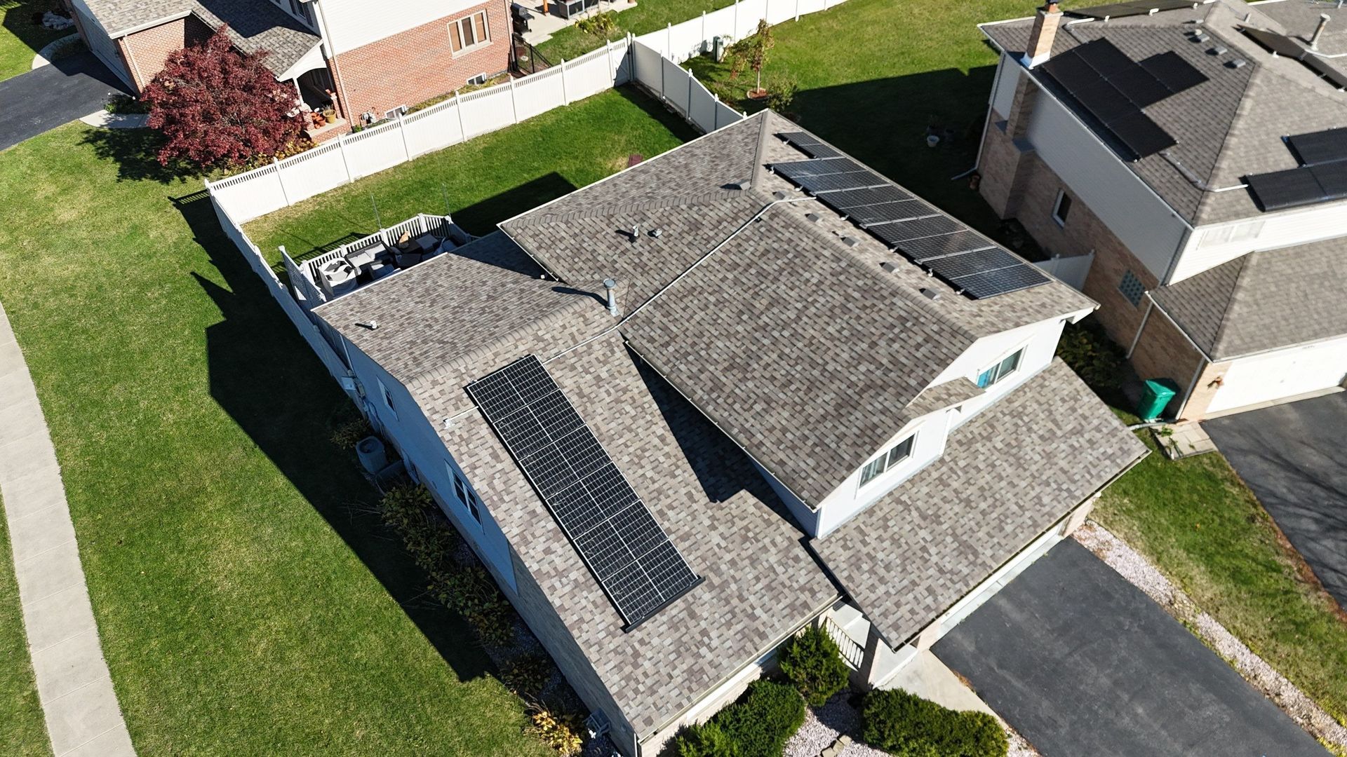 Overhead view of a house with solar panels on the roof, green lawn, and a driveway.