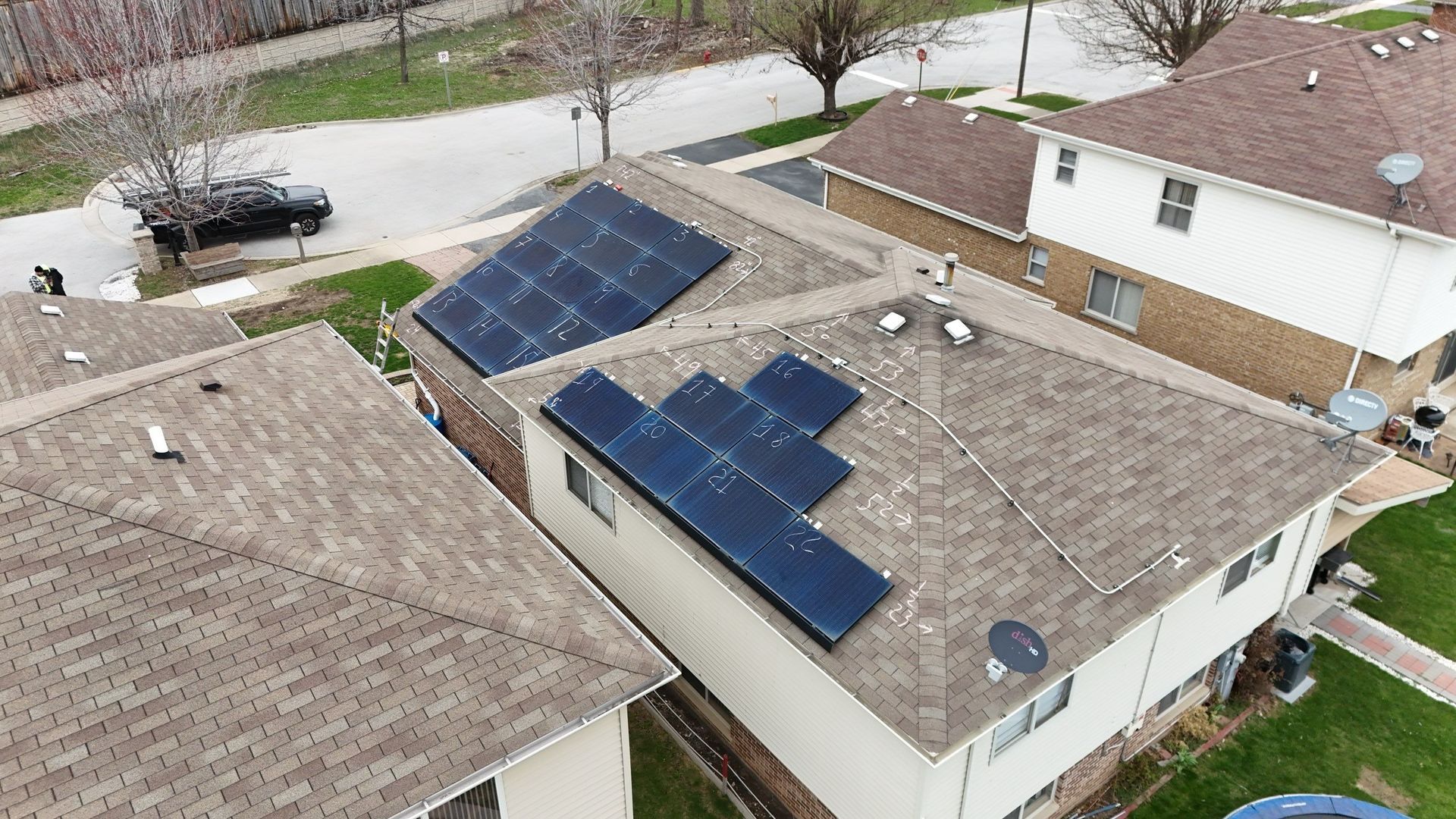 Aerial view of a house rooftop with several dark solar panels installed, showing an eco-friendly energy source.