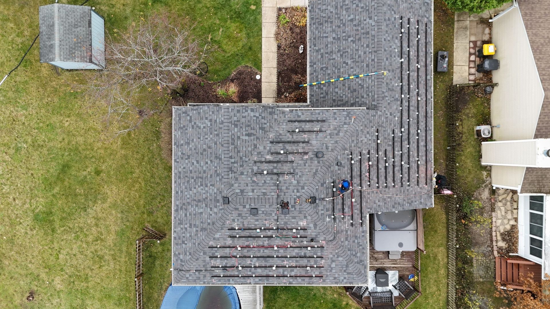 Overhead view of a house roof partially under construction. The roof is gray and some shingles are missing.
