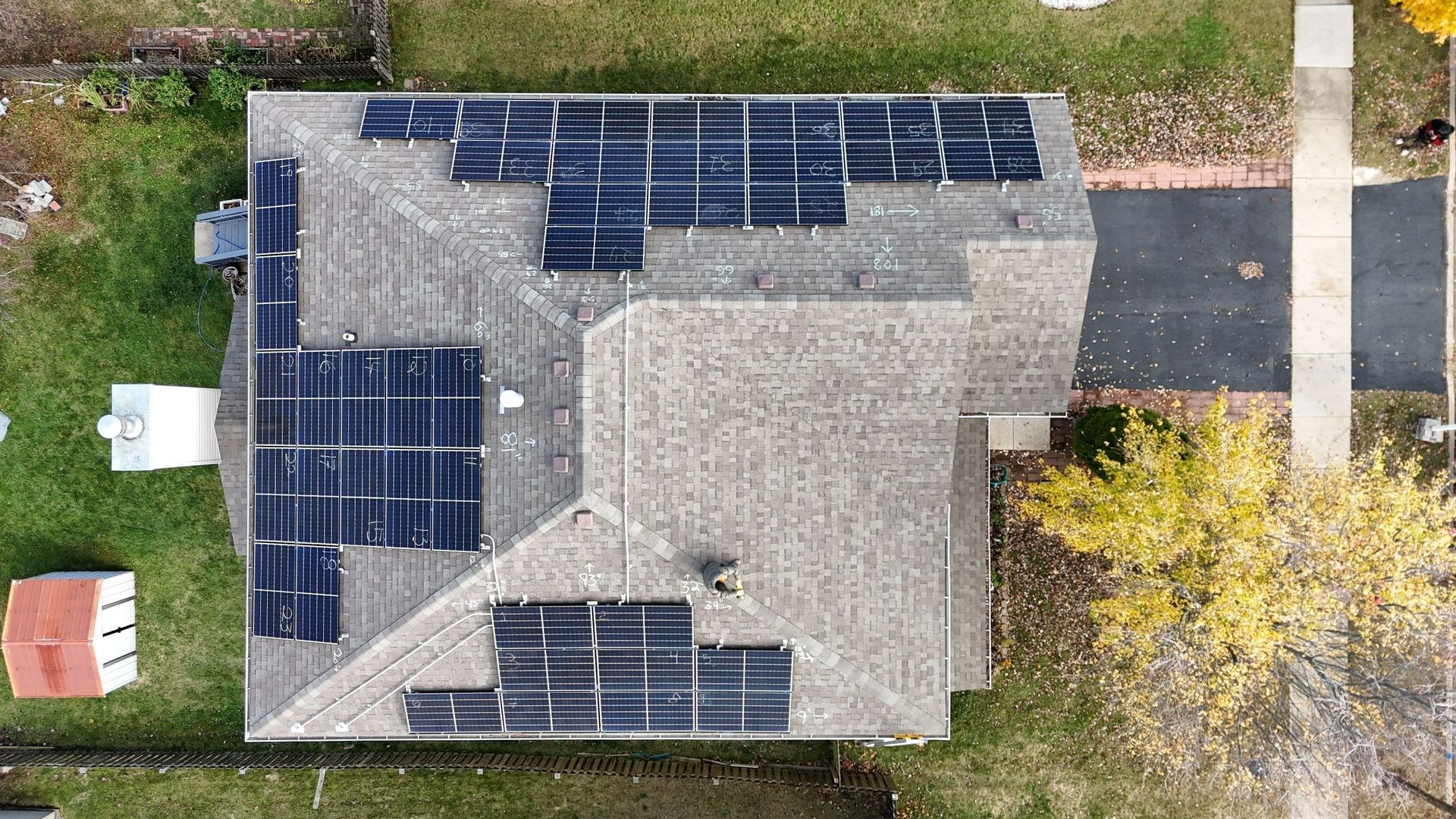 Overhead view of a house with solar panels on the roof, in a residential setting.