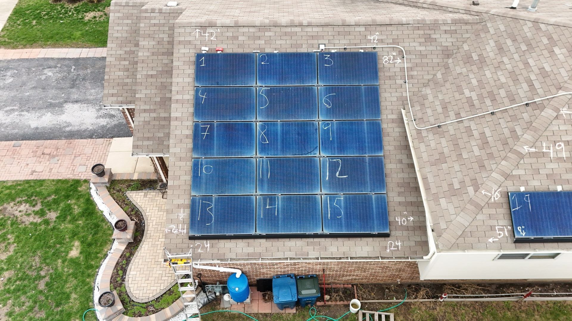 Overhead view of solar panels installed on a residential rooftop. Panels are numbered and blue.