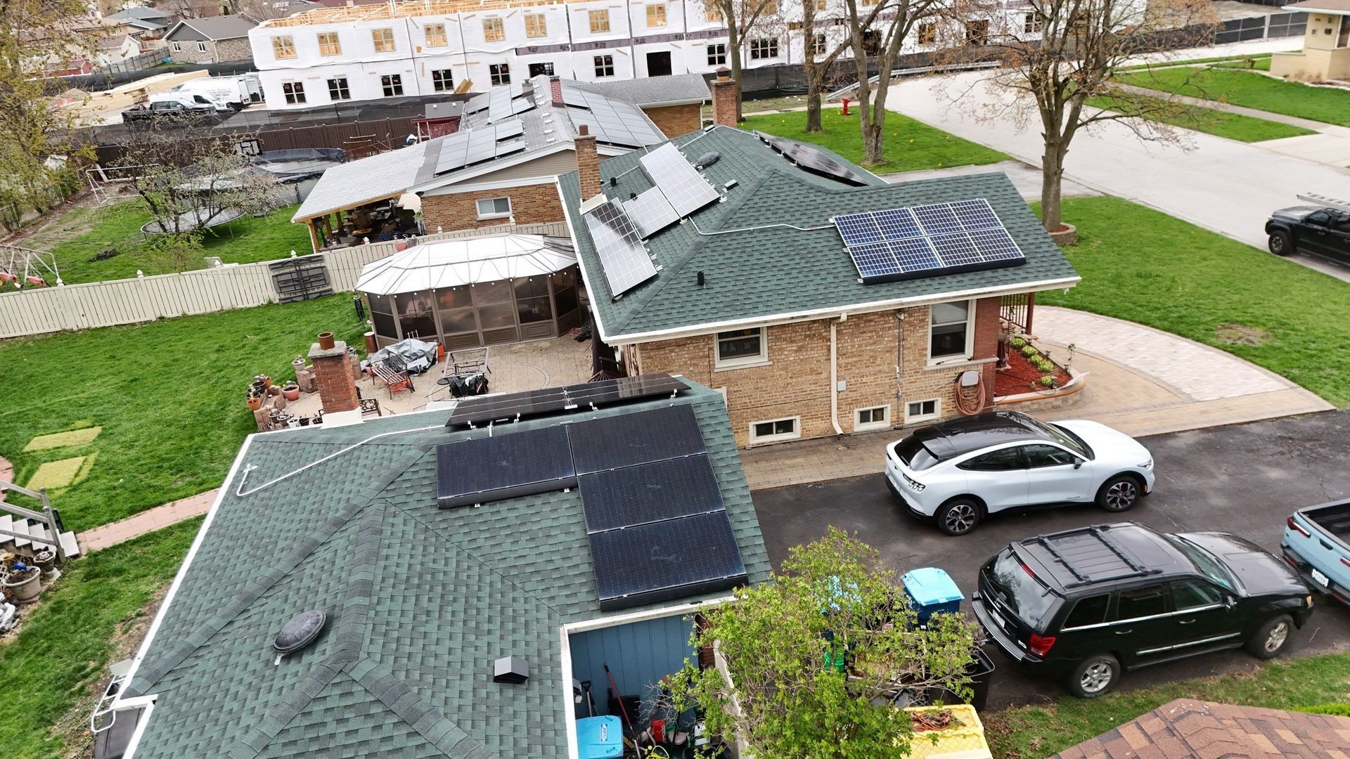 Houses with solar panels on their roofs; a white SUV and a black SUV are parked in the driveway.