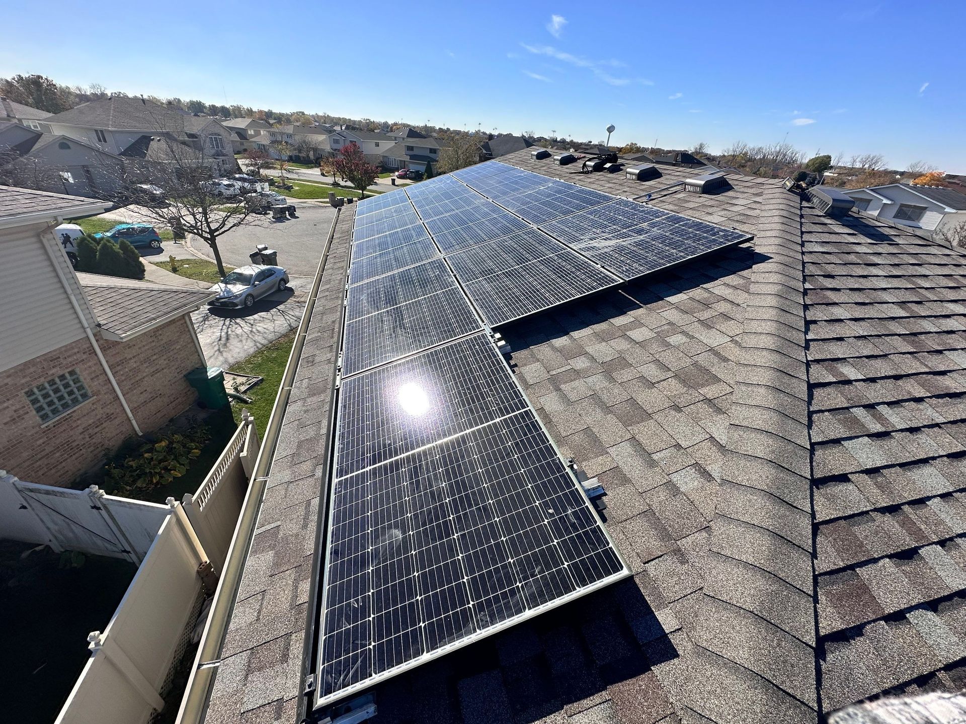 Solar panels installed on a residential shingled roof under a blue sky.