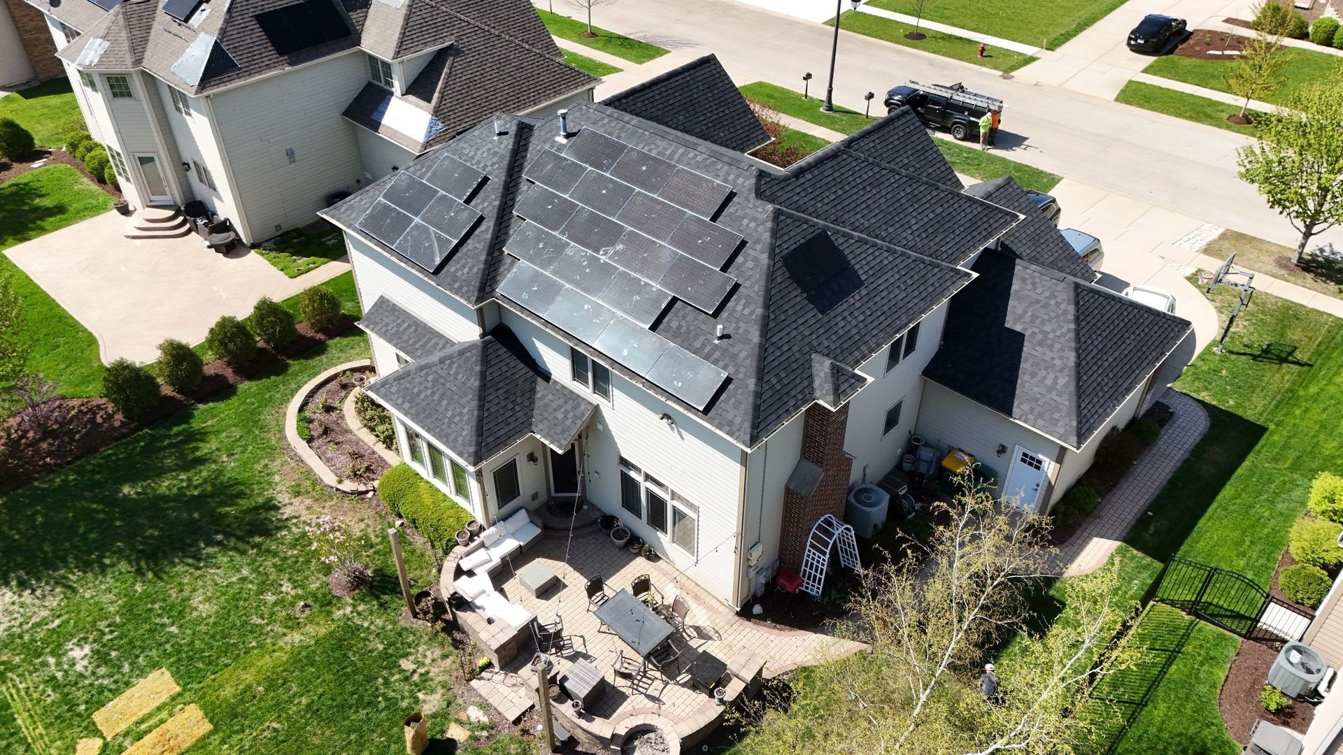 Overhead view of a house with solar panels on the roof and a patio in the backyard.