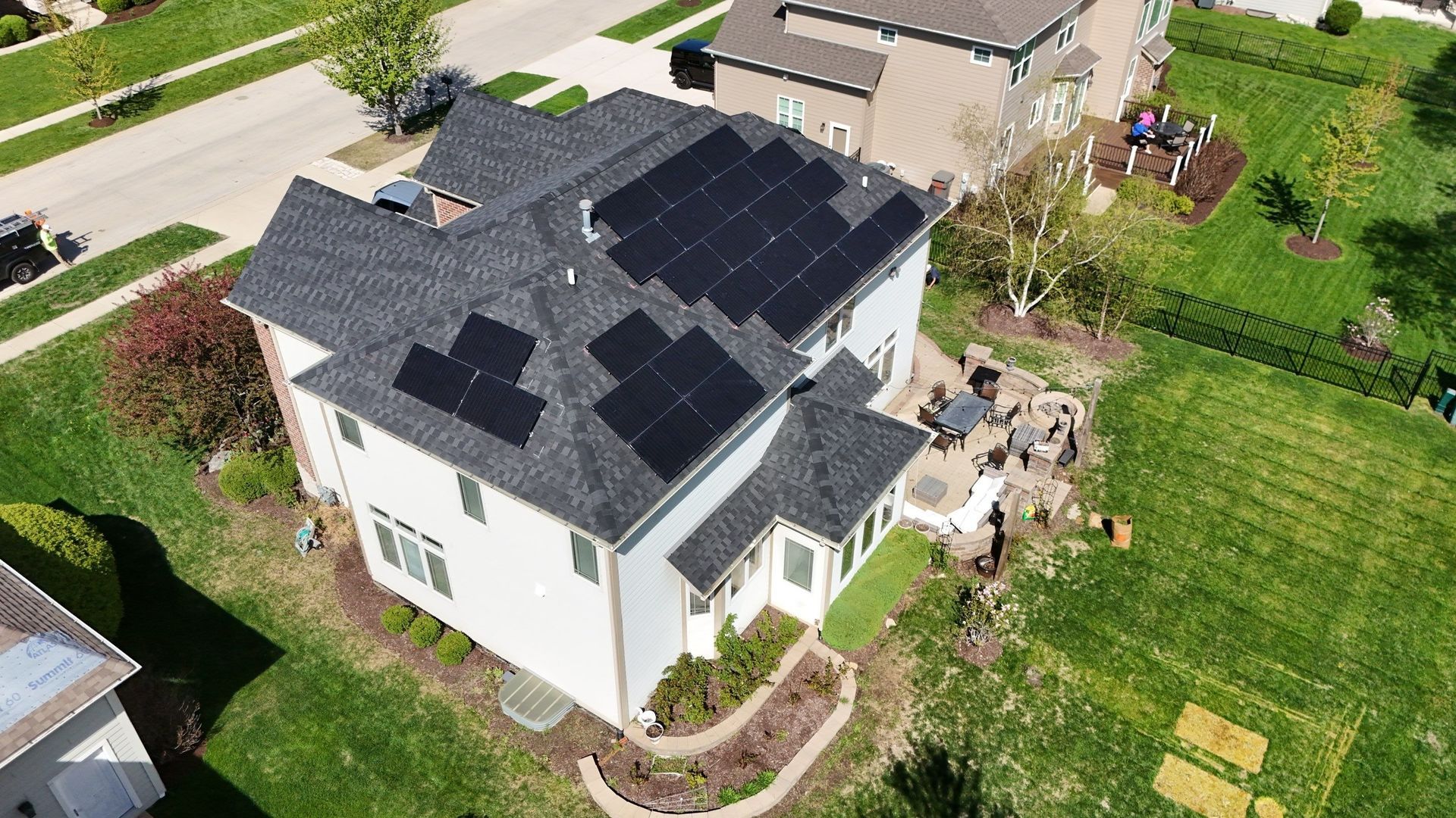 House with solar panels on the roof, in a green yard.