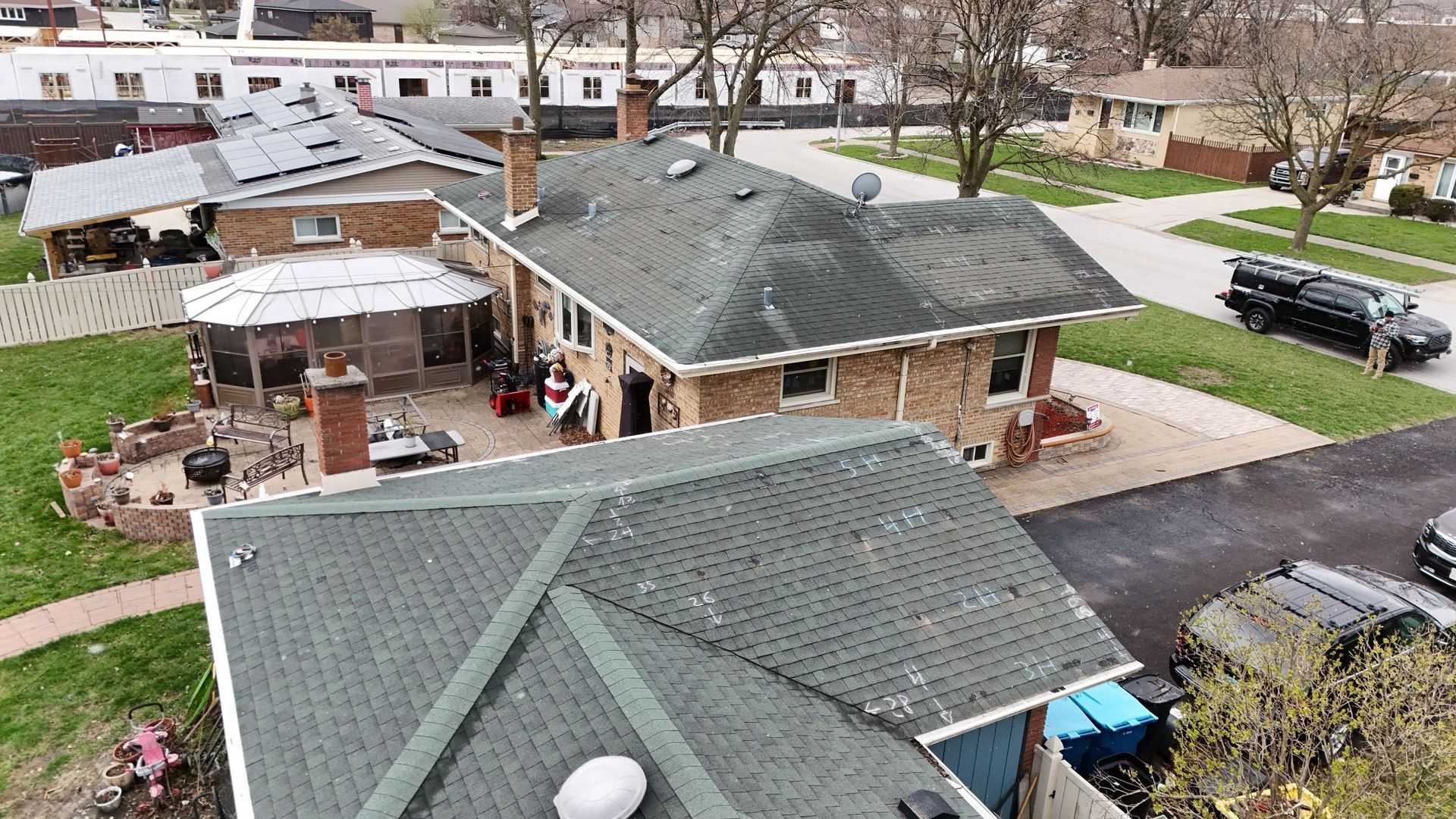 Aerial view of brick houses with green roofs and driveways in a suburban setting.