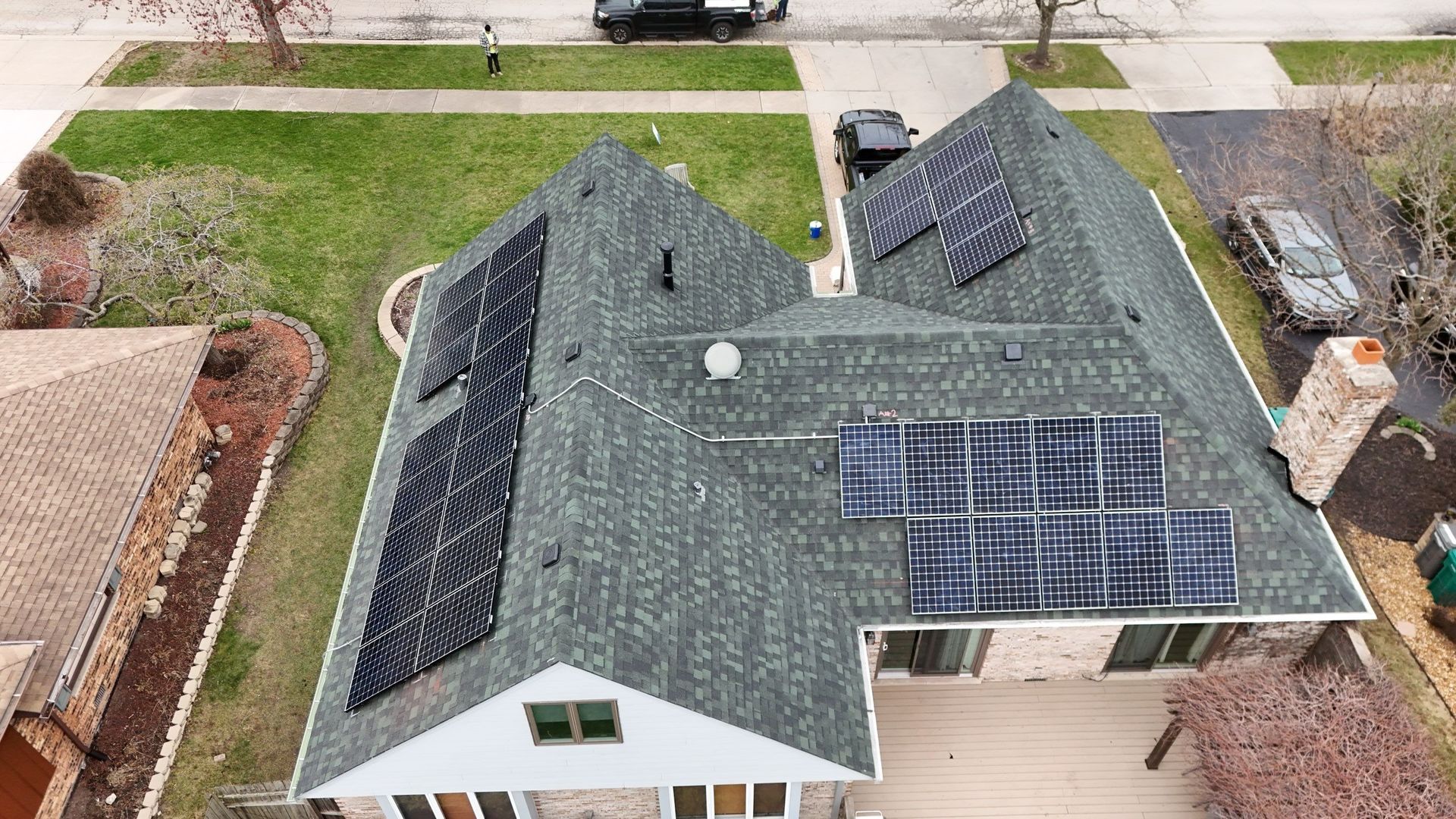 Overhead view of a house with solar panels on the roof and a car parked in the driveway.