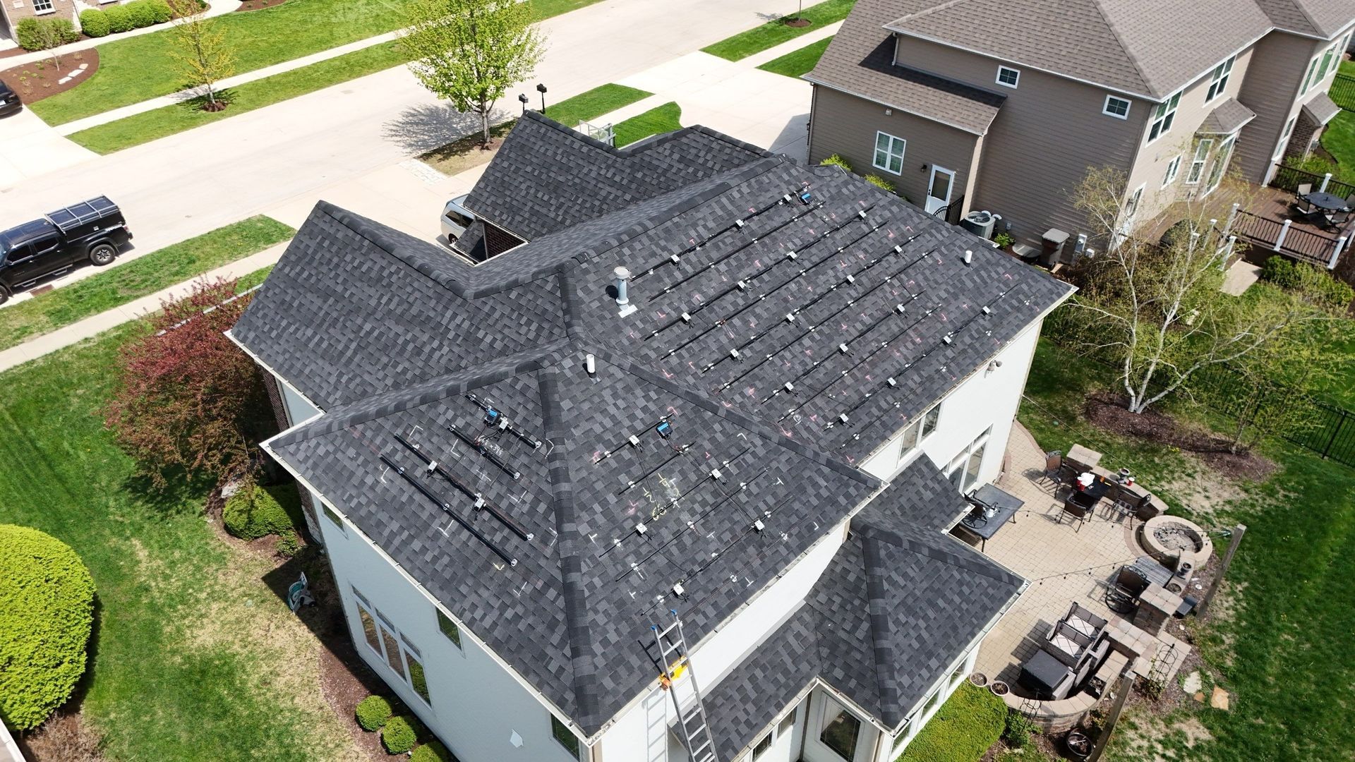 Overhead view of a two-story house with dark shingle roof, solar panels, and green lawn.
