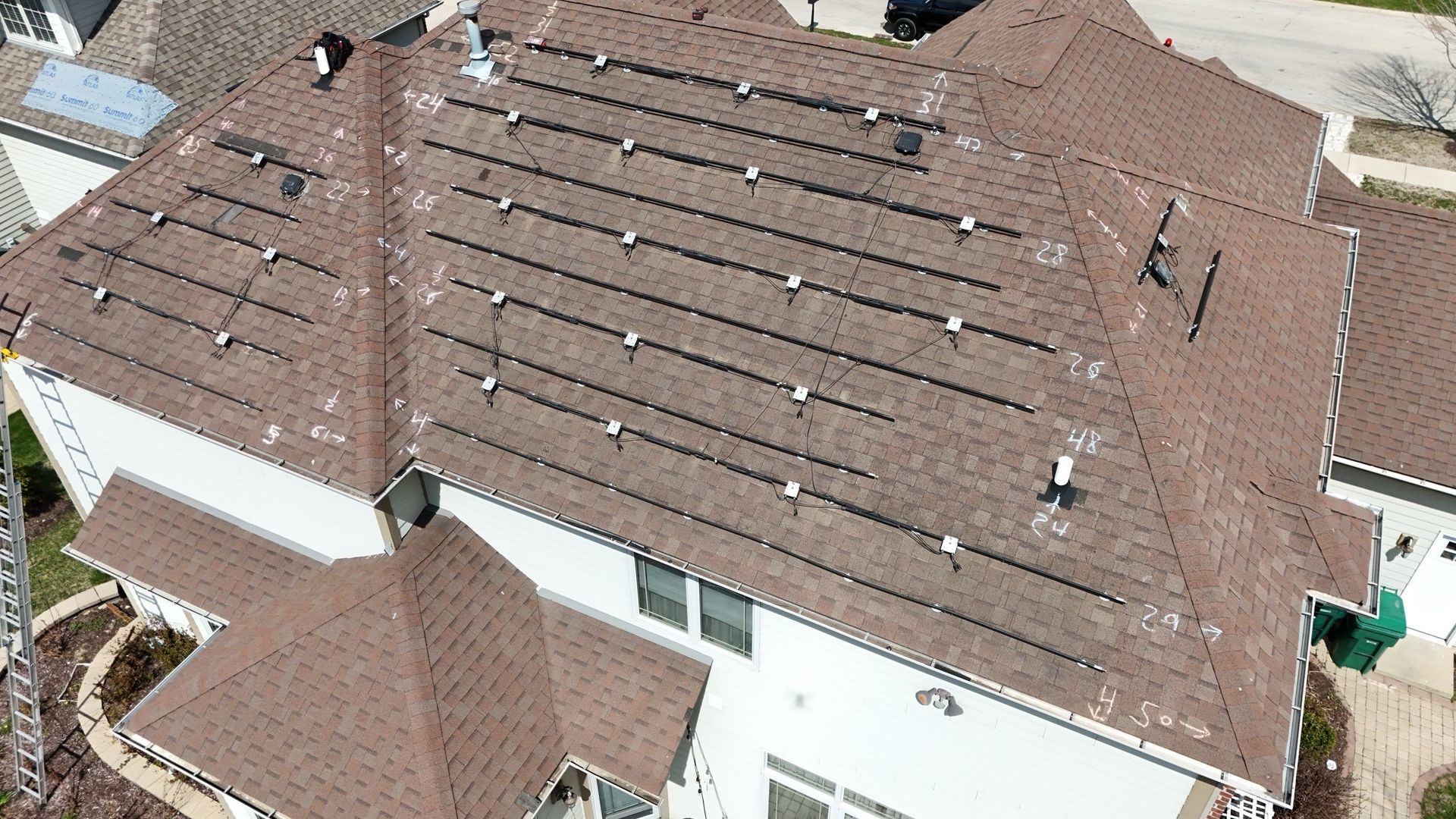 Brown roof with solar panels. White house exterior. Aerial view.
