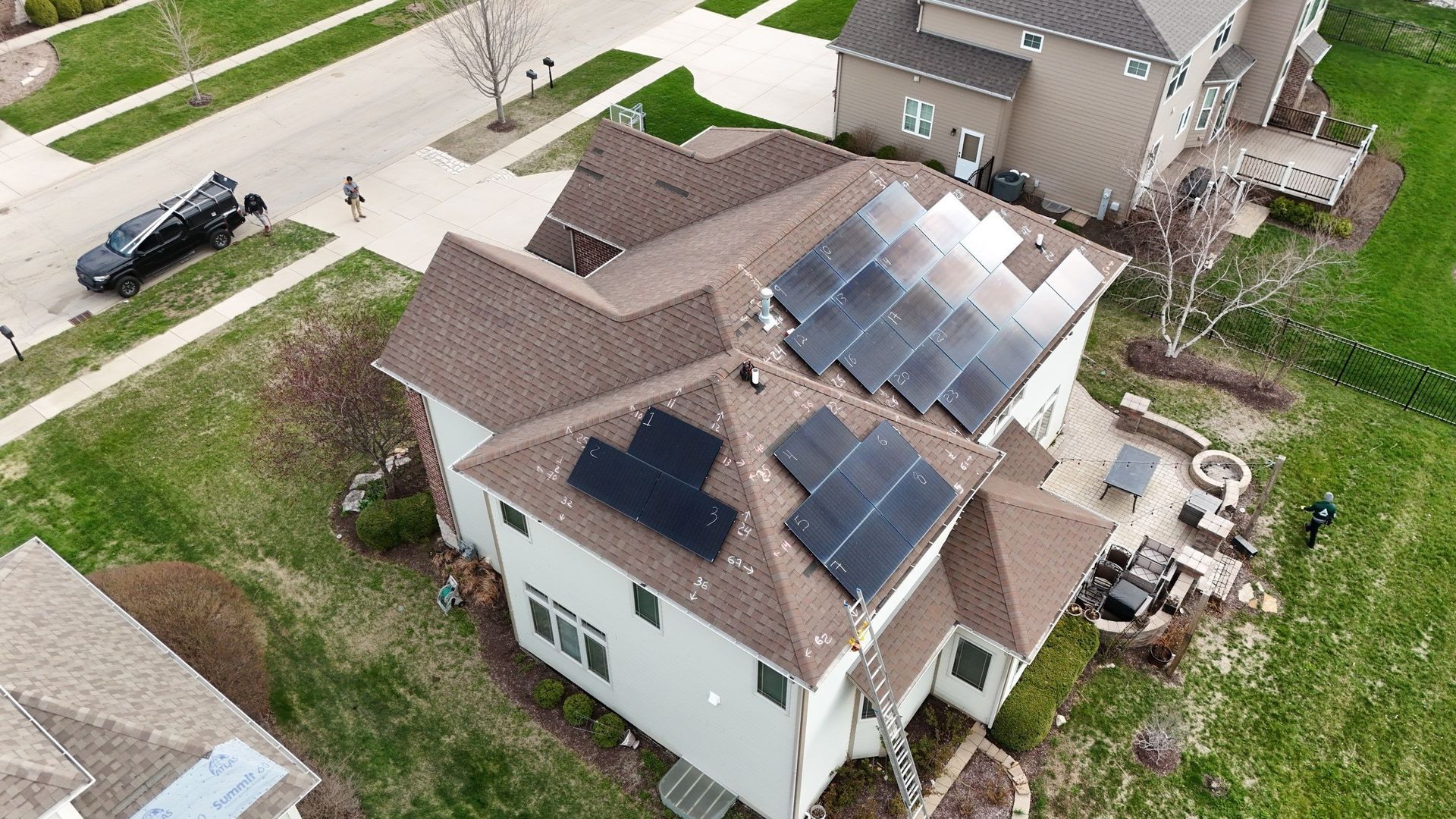 Aerial view of a house with solar panels on the roof, located in a suburban neighborhood.