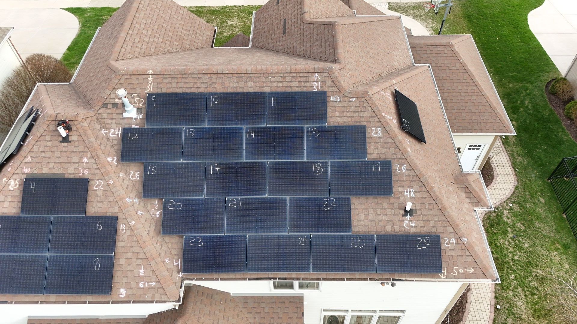 Solar panels installed on a brown shingled roof of a residential house.