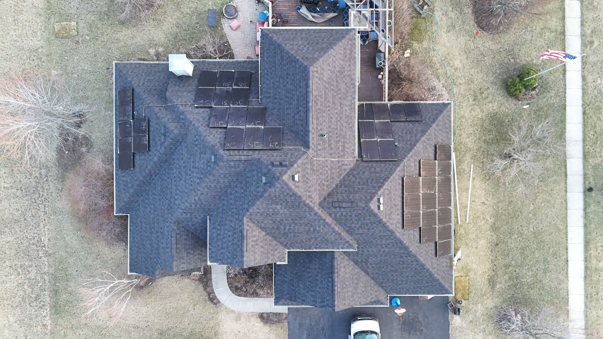 Overhead view of a house with solar panels on the roof and a flag waving nearby.