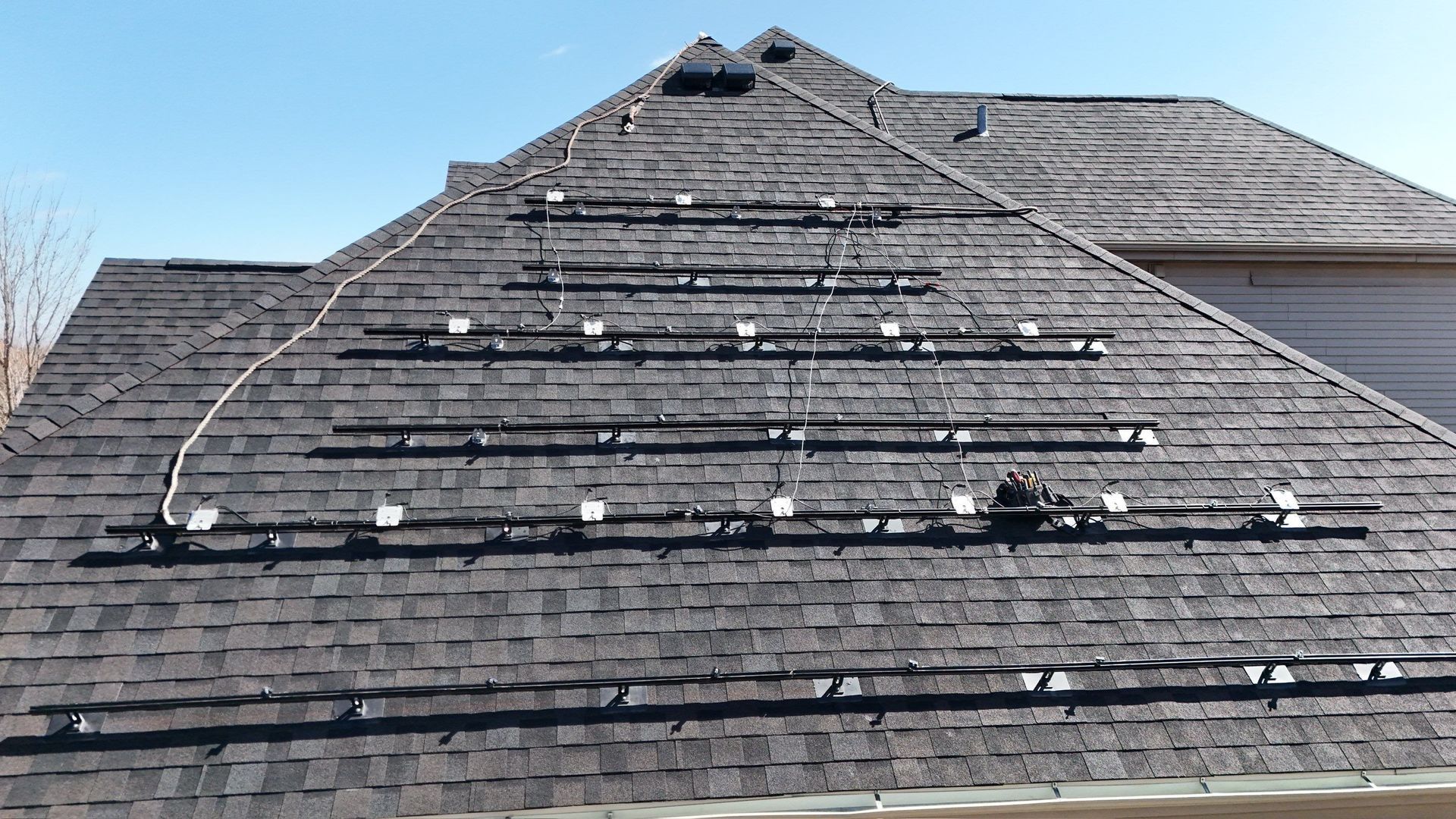 Solar panels mounted on a dark shingle roof on a sunny day.