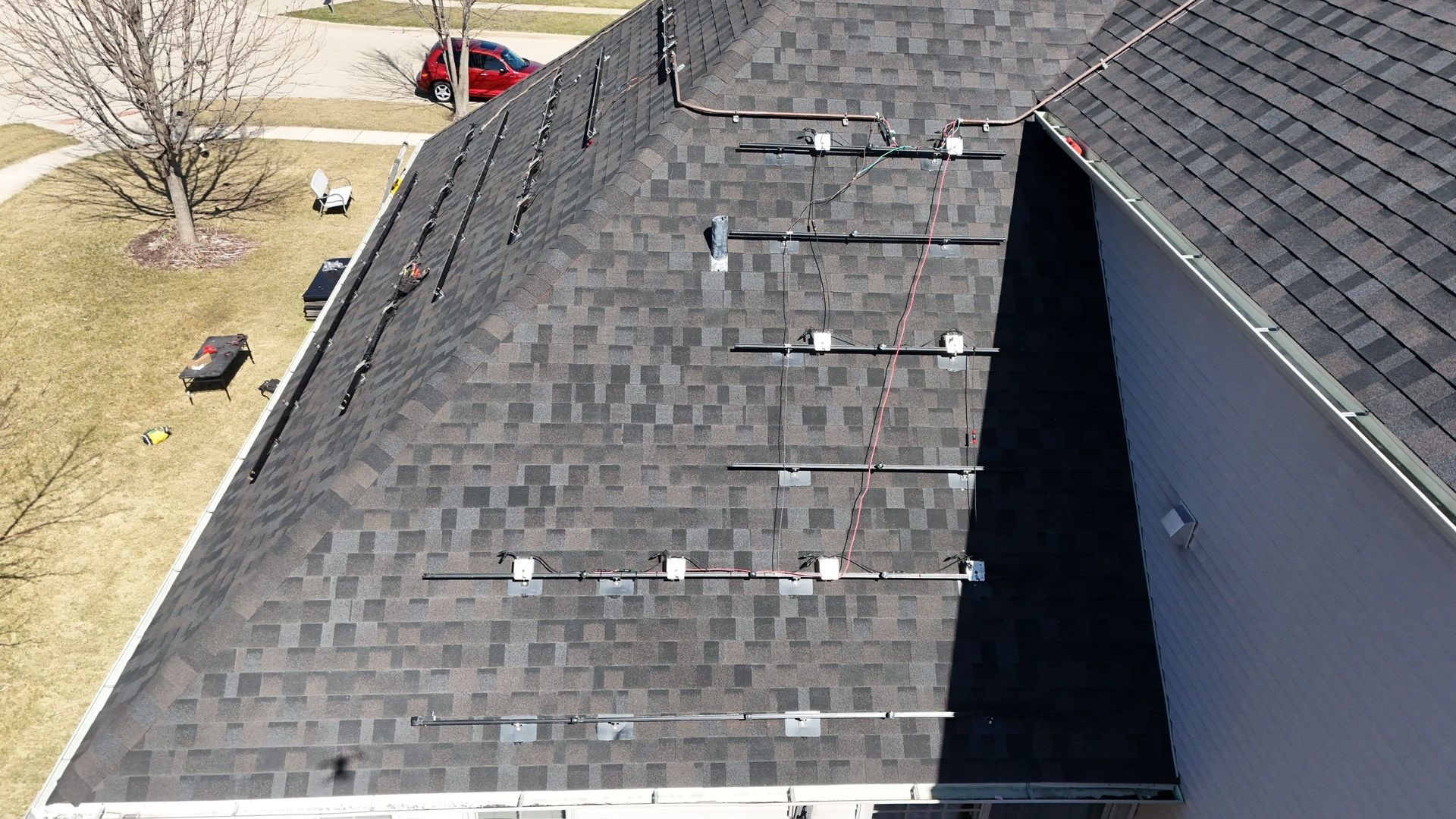 A gray asphalt shingle roof with metal rails installed, likely for solar panels.