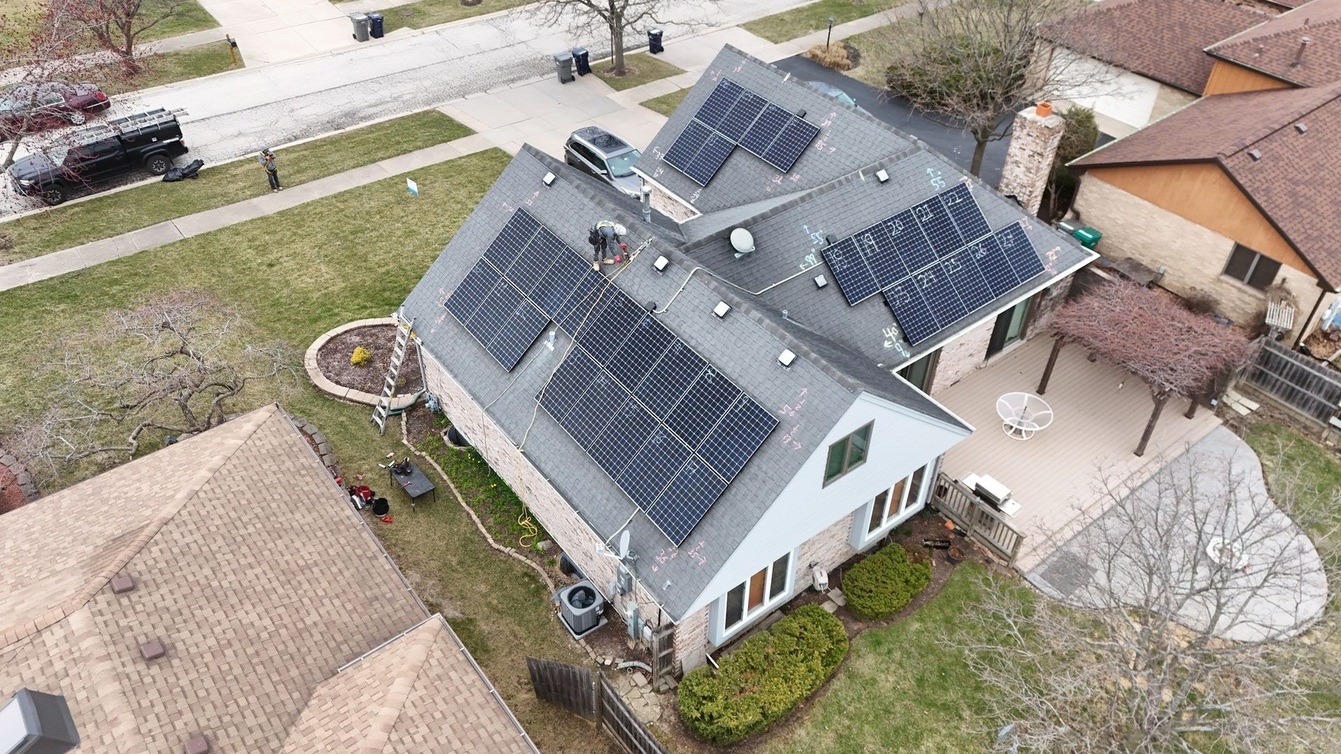 Aerial view of a house with solar panels on the roof, in a suburban neighborhood.