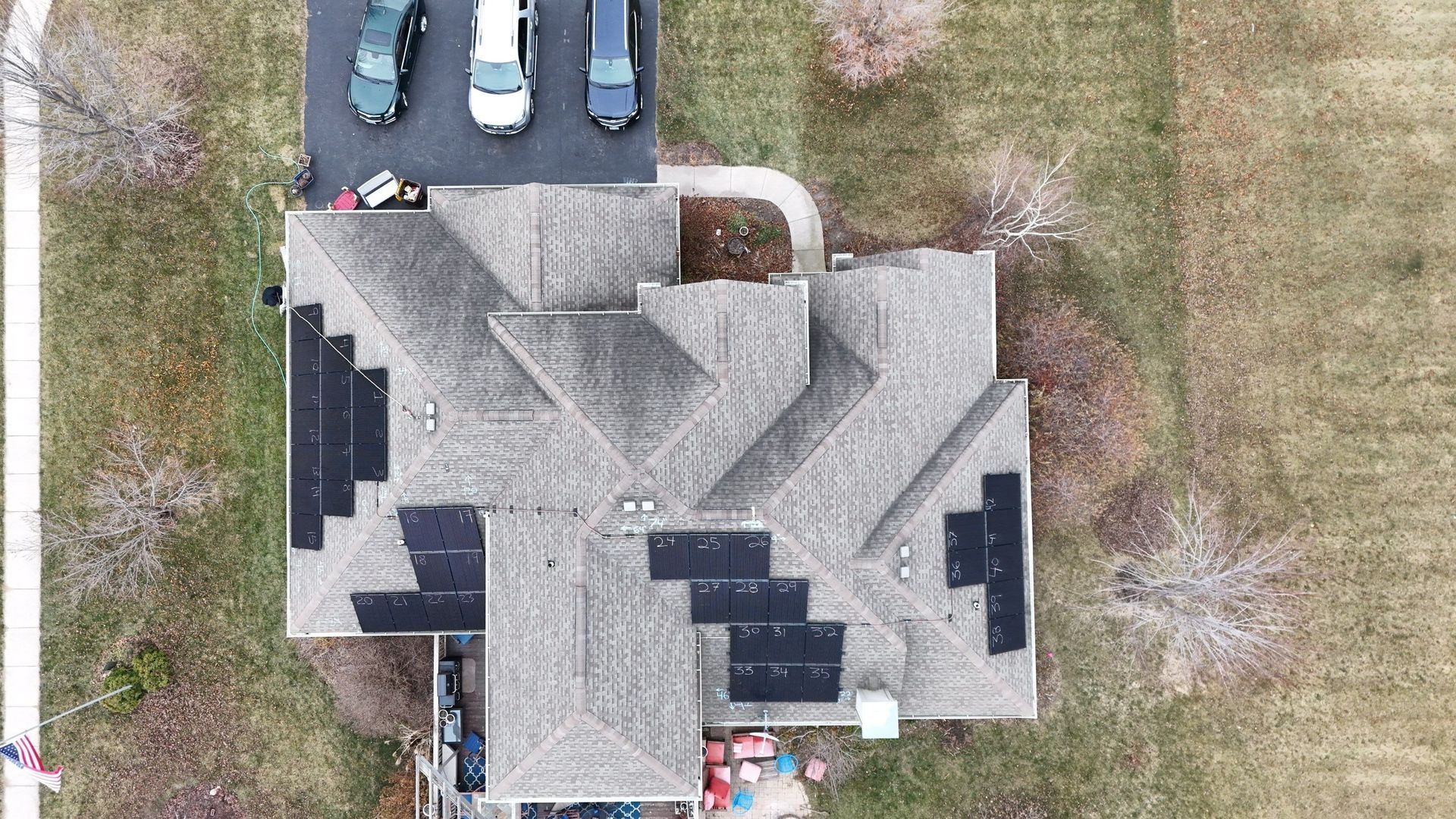 Overhead view of house with solar panels on the roof and cars in the driveway.