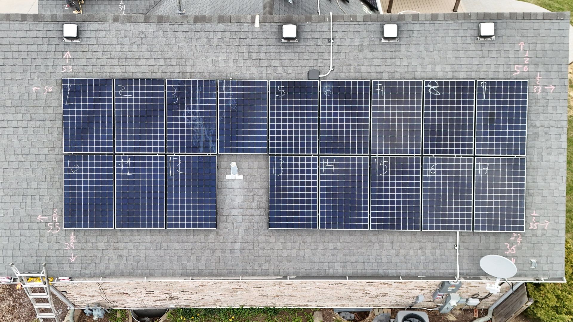 Overhead view of solar panels on a gray shingled roof of a residential house.