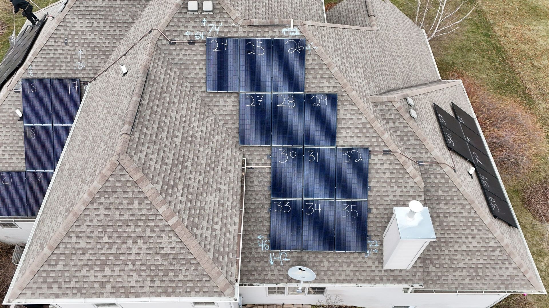 Solar panels on a brown shingle roof; a white chimney is visible.