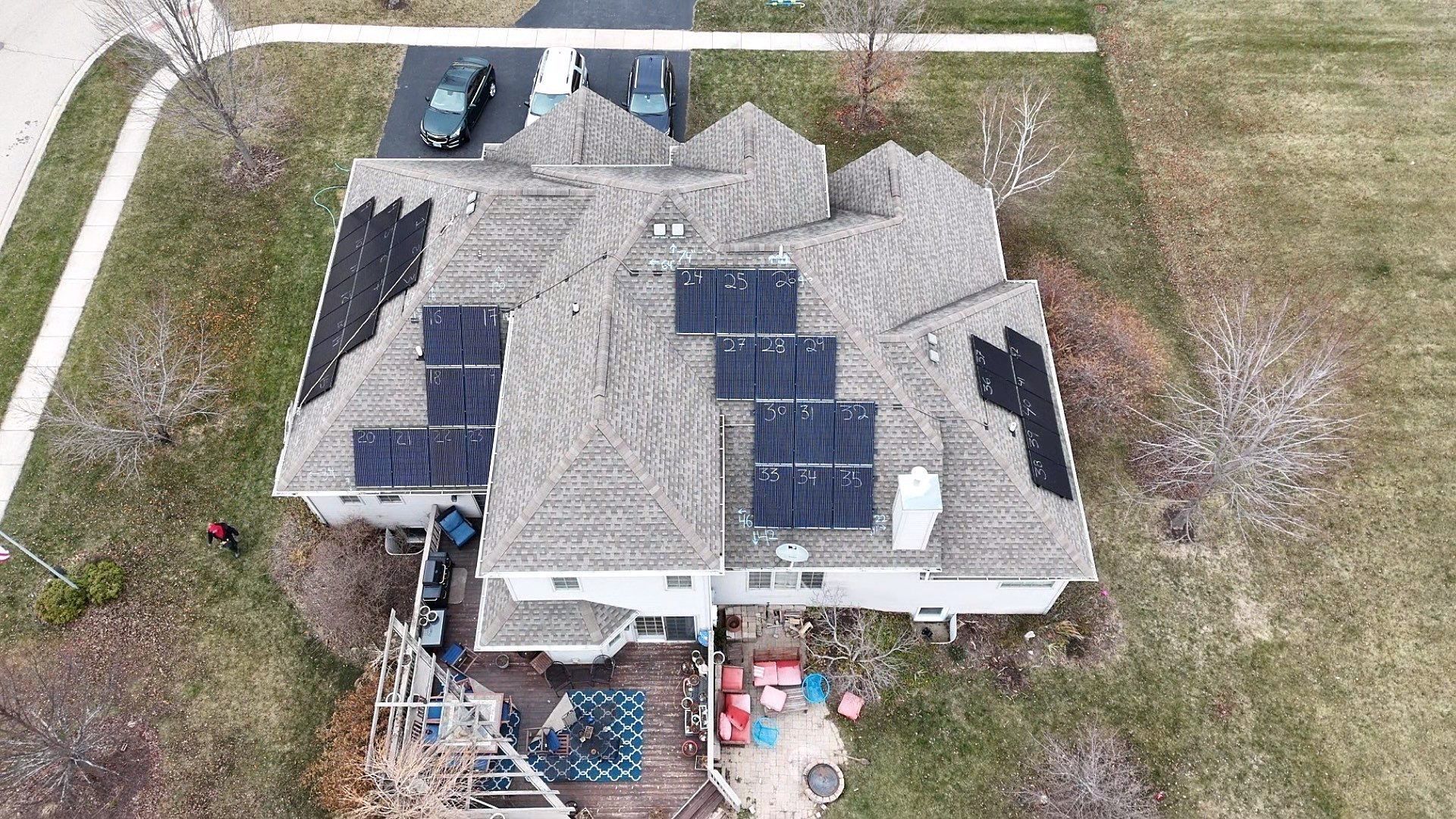 Aerial view of a house with solar panels on the roof, black and gray color scheme.