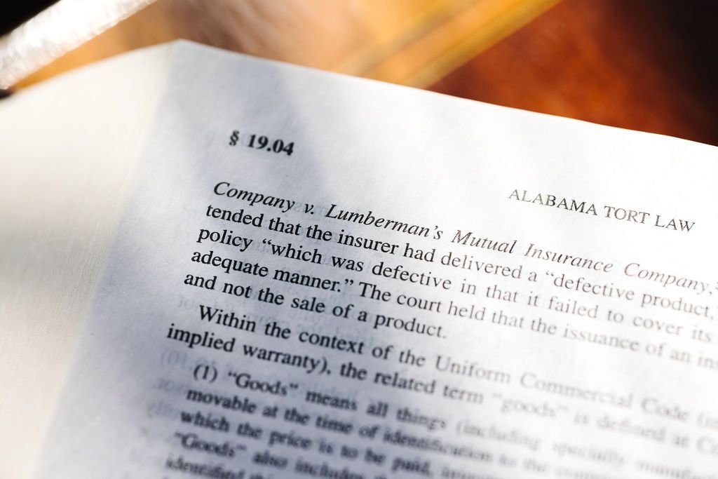 An Alabama Torts Law book is open with text blurred.