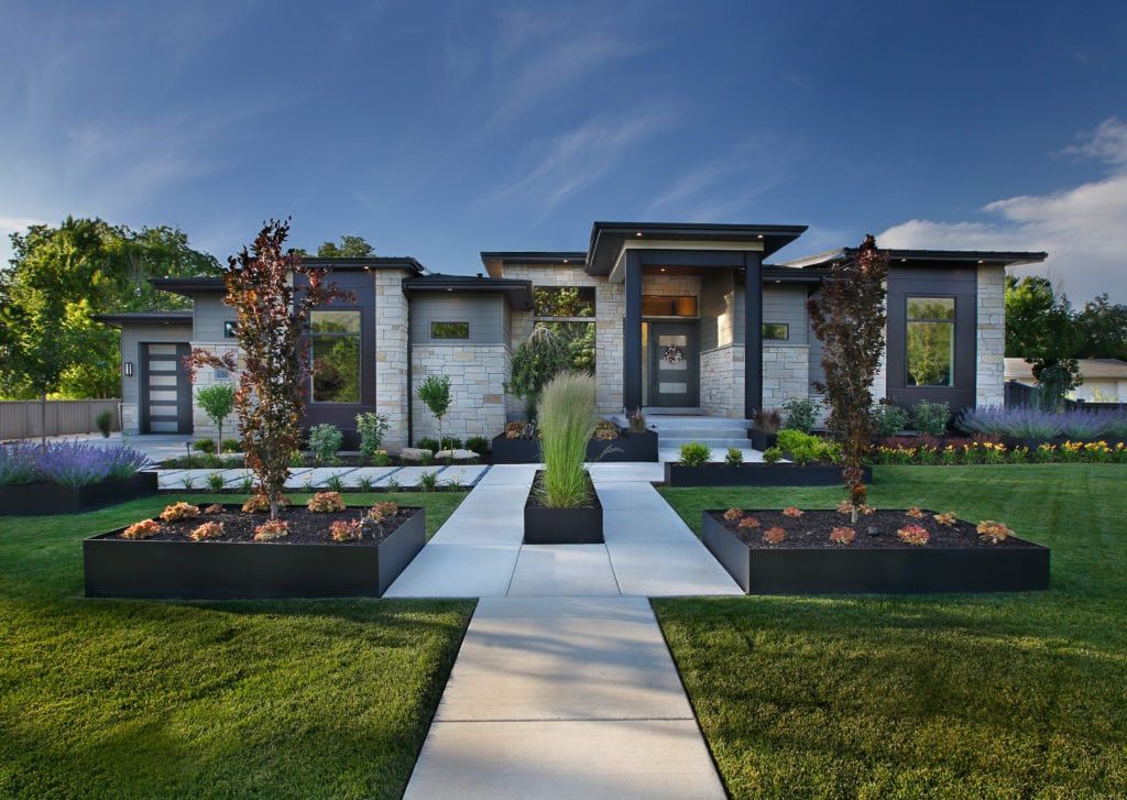 A large modern house with a concrete walkway leading to it.