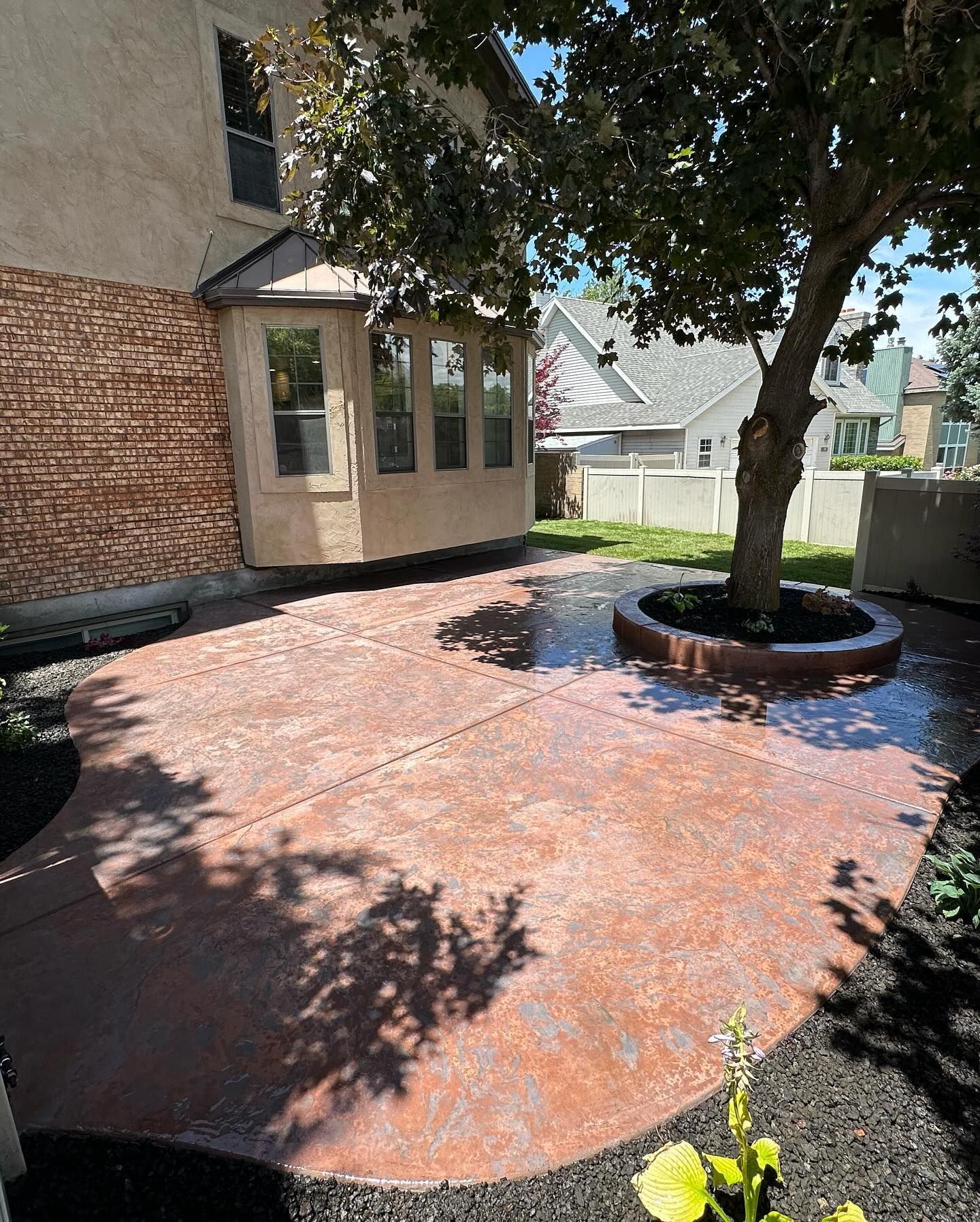 A patio with a tree in the middle of it in front of a house.