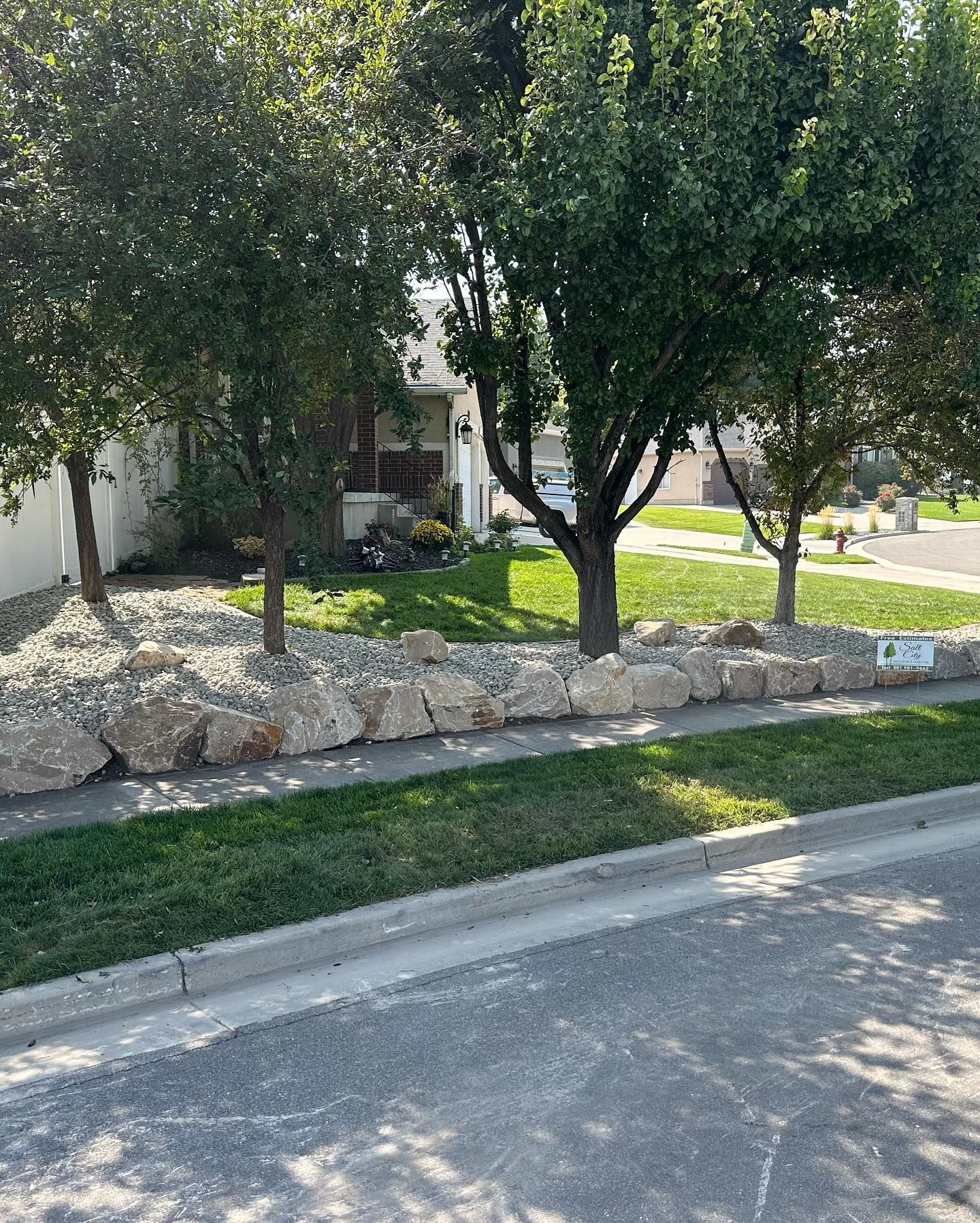A house with a lot of trees and rocks in front of it.